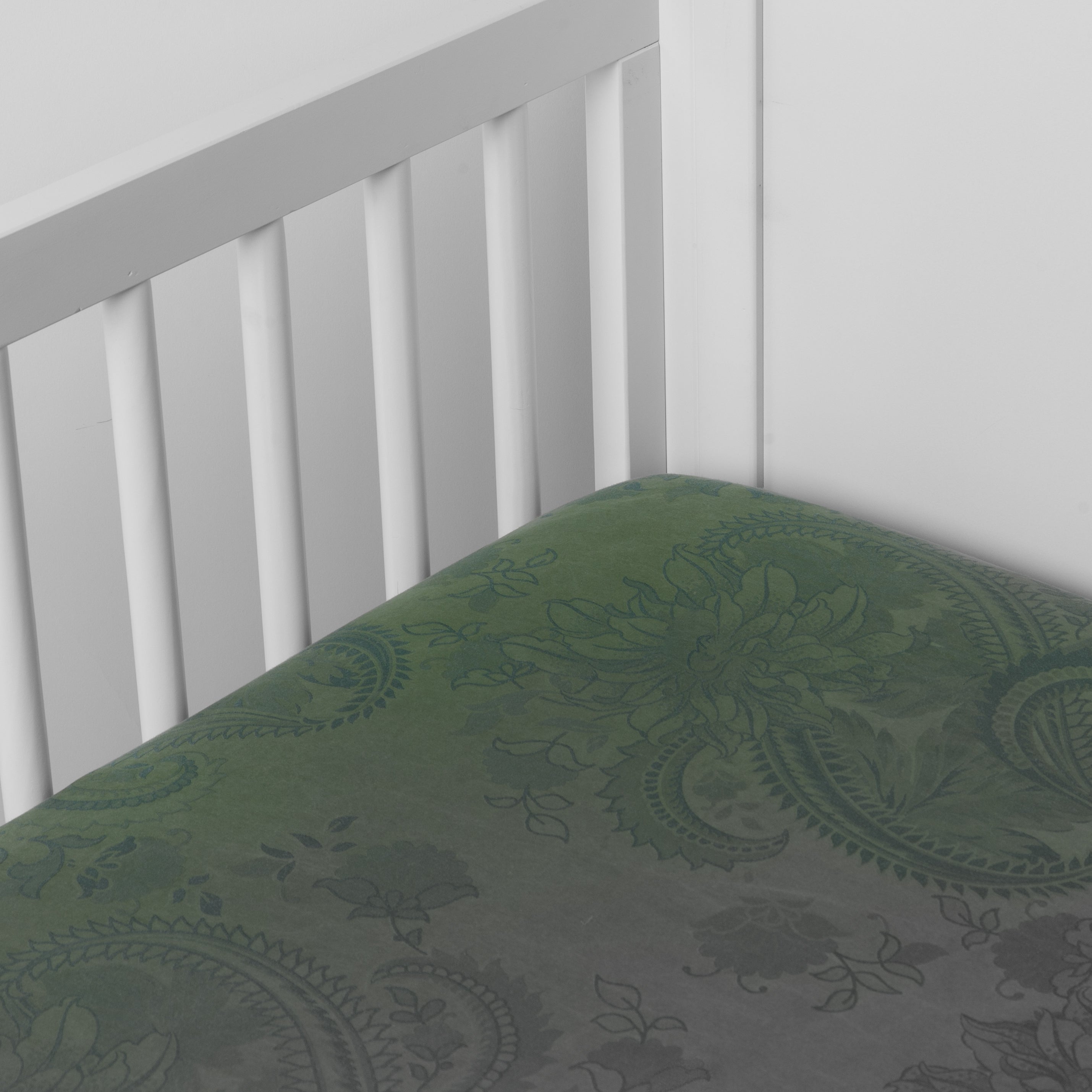 Jade: a silk and tencel™ crib sheet shown slightly overhread and shot into the corner of a white crib. 