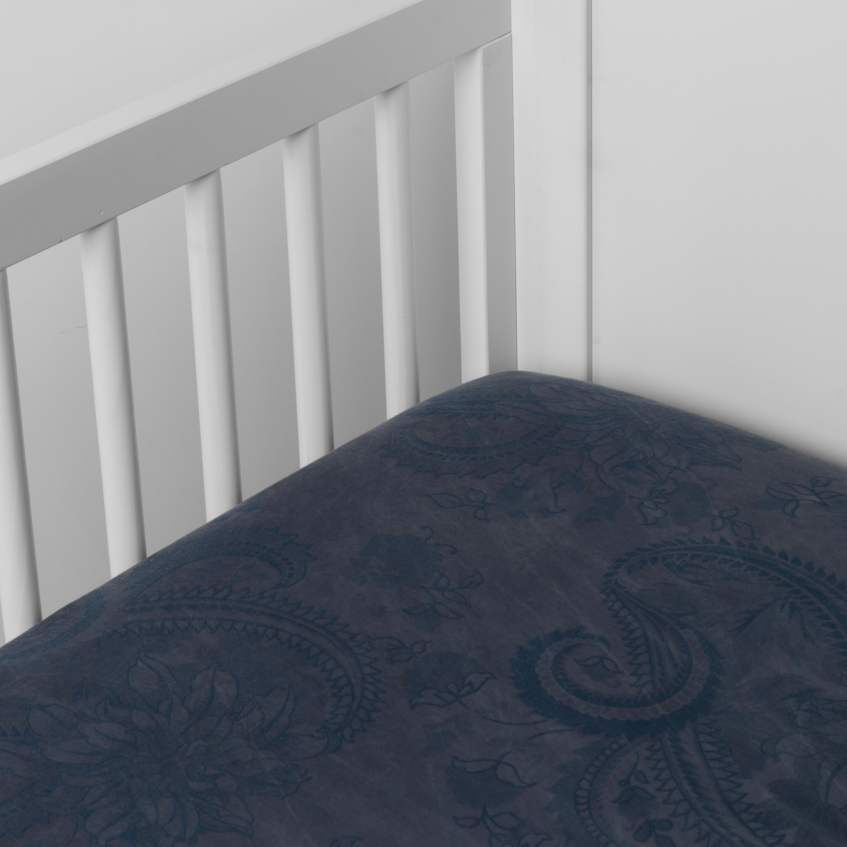 Midnight:  silk and tencel™ blend jacquard crib sheet shot from above at a slight angle into the corner of a white crib. 