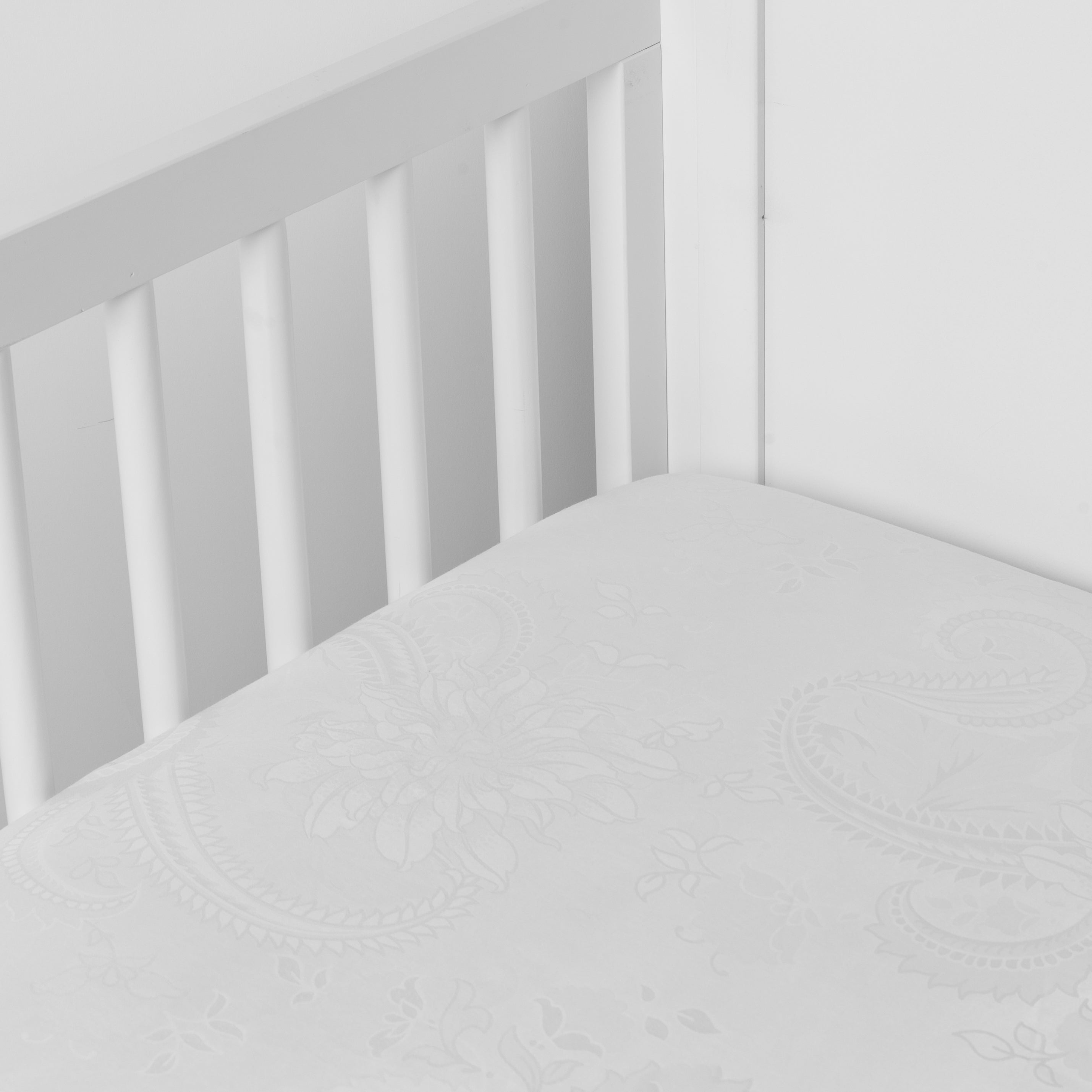 Winter White: a silk and tencel™ crib sheet shown slightly overhread and shot into the corner of a white crib. 