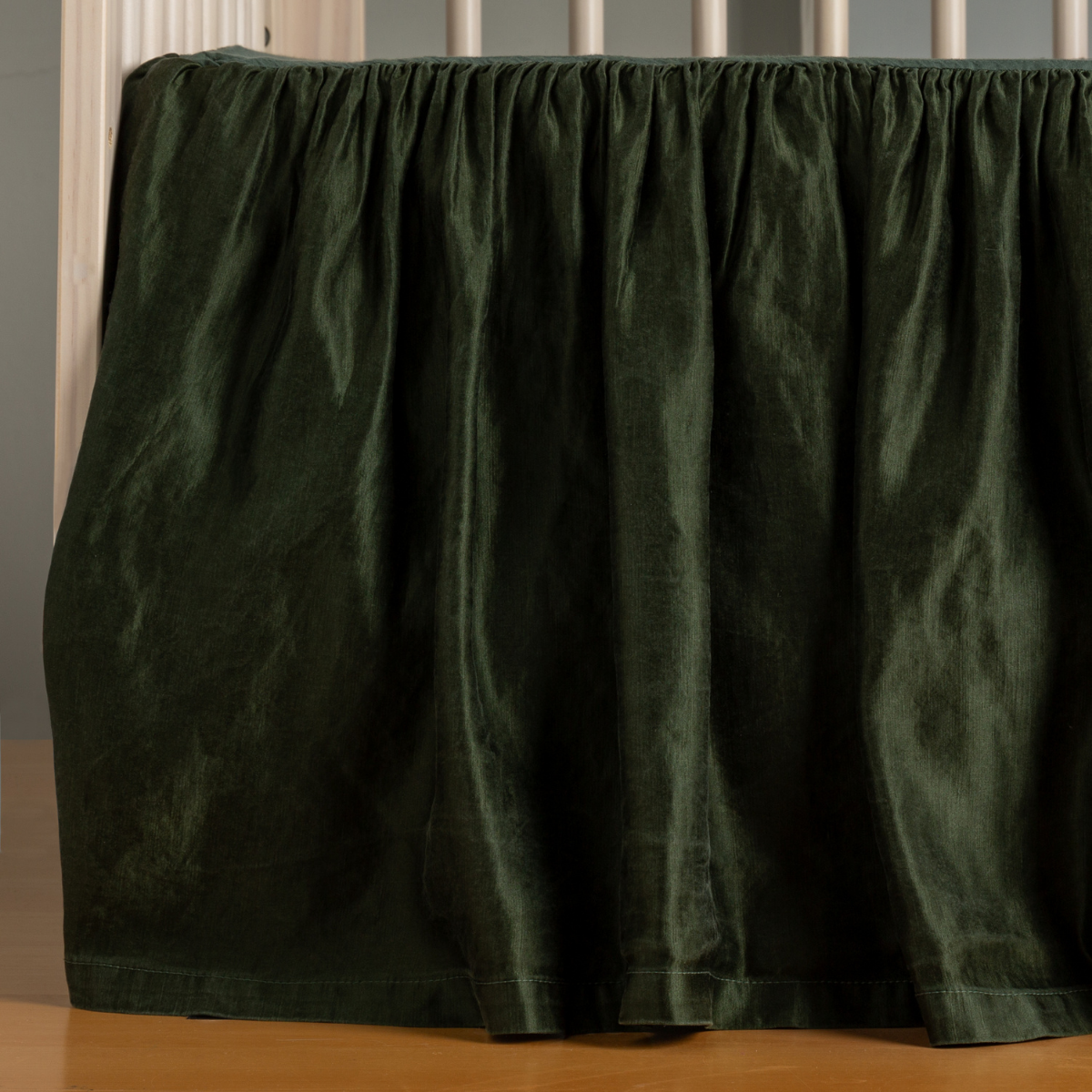 Juniper: charmeuse crib skirt on a natural wood crib without a mattress, gently skimming the floor. 