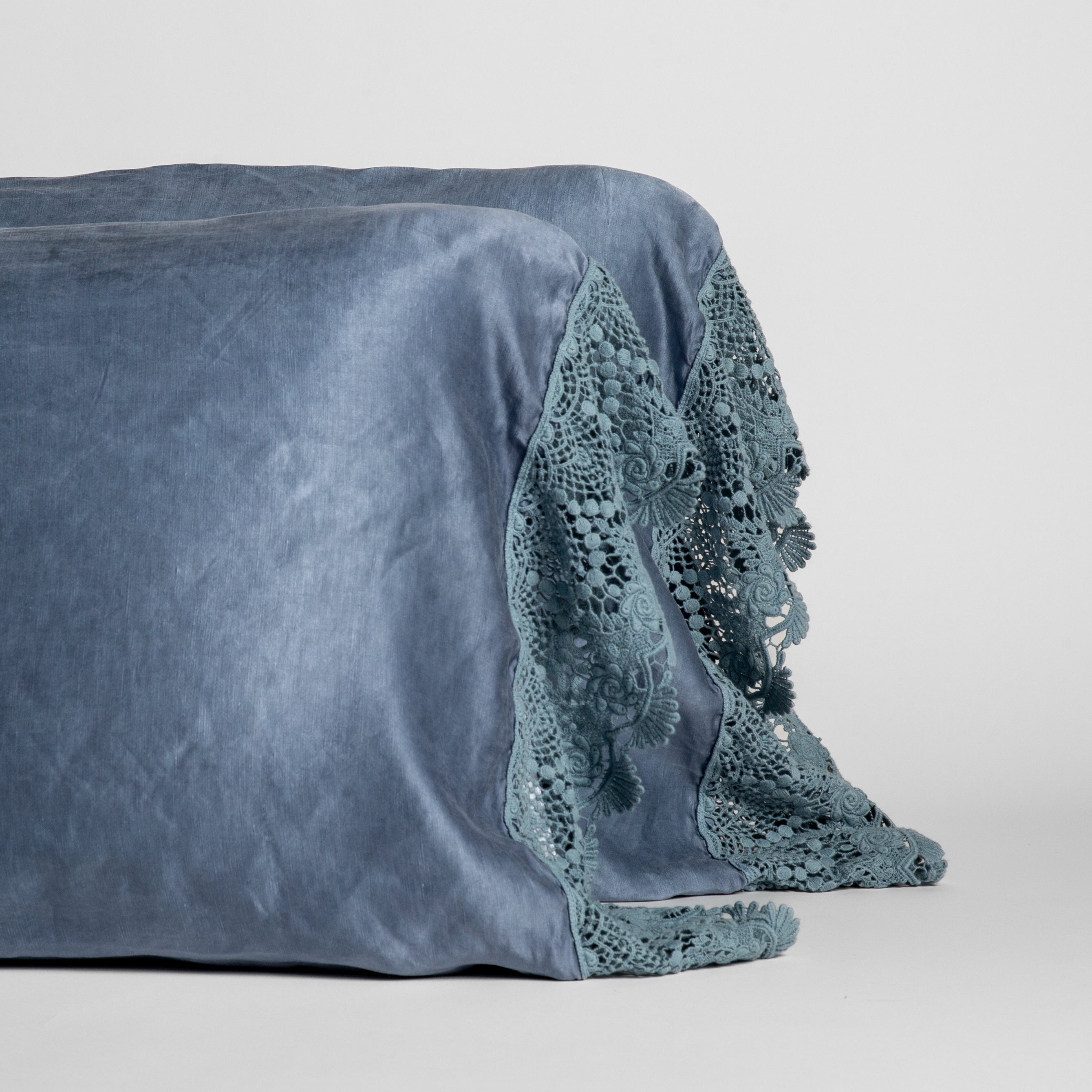 Tahoe Blue: Tahoe Blue charmeuse with lace trimmed pillowcases standing upright against a white background. 