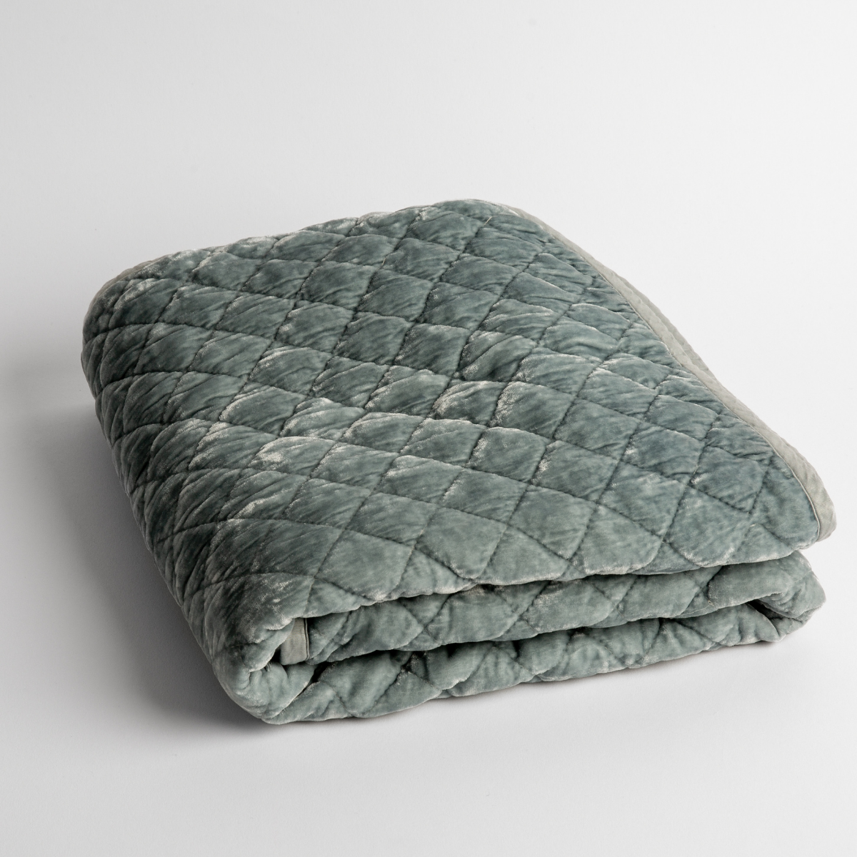 Cloud:   a folded quilted silk velvet baby blanket shown from overhead to showcase quilting  pattern and texture. 