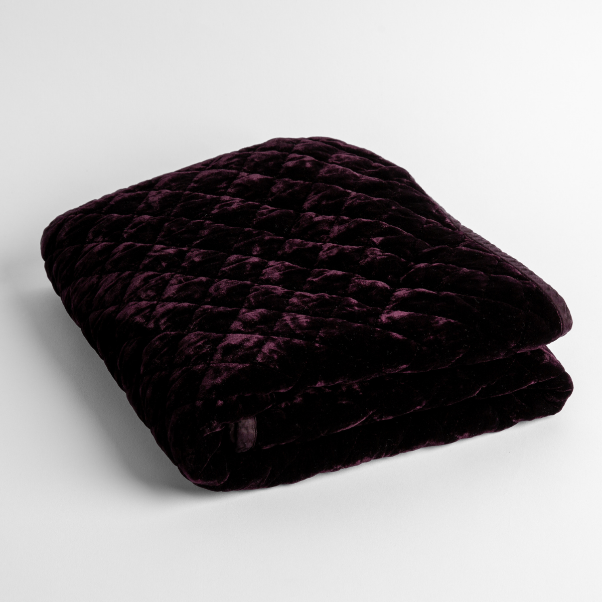Fig:   a folded quilted silk velvet baby blanket shown from overhead to showcase quilting  pattern and texture. 