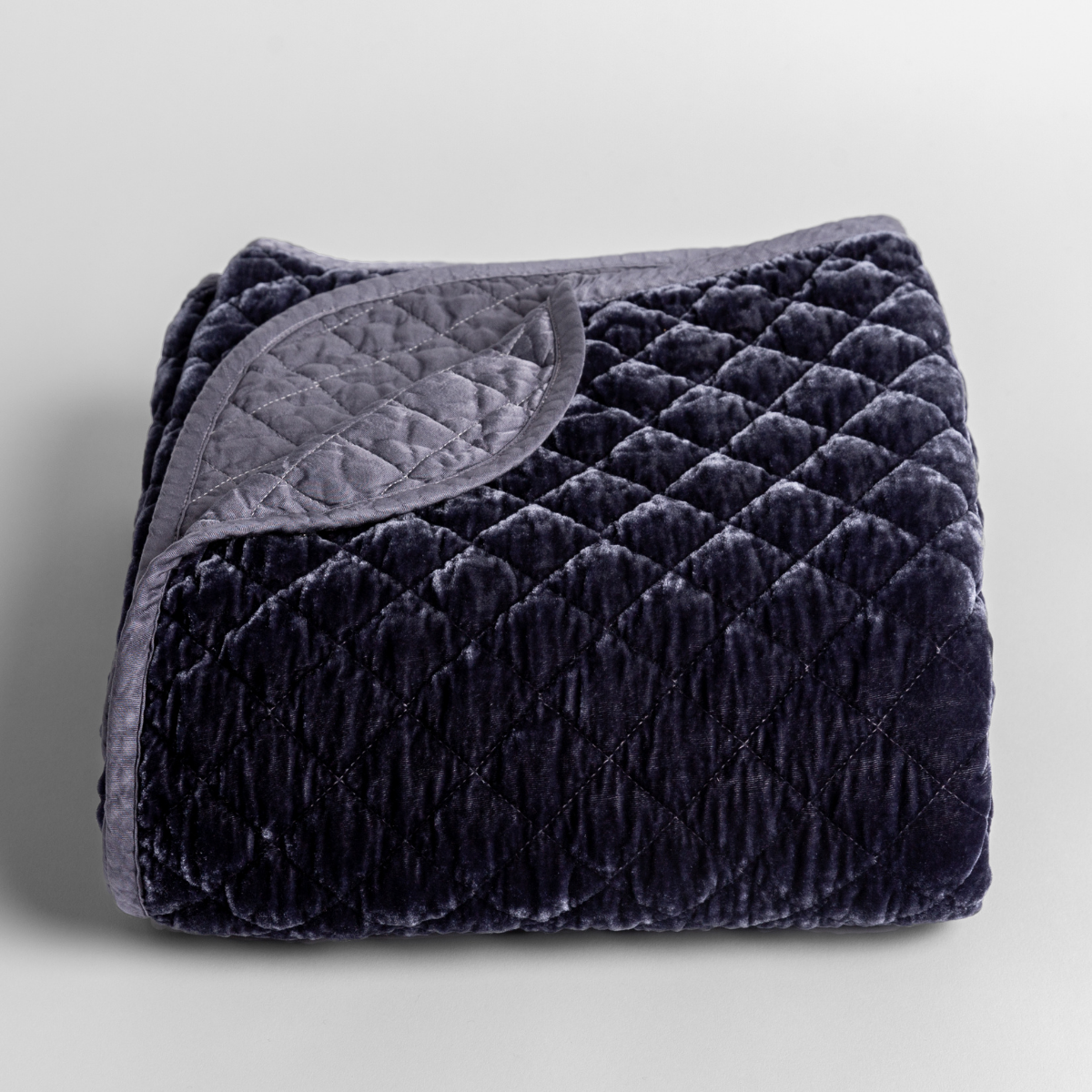 French Lavender: quilted silk velvet quilted blanket folded with its corner folded back to reveal a satin back and binding. 