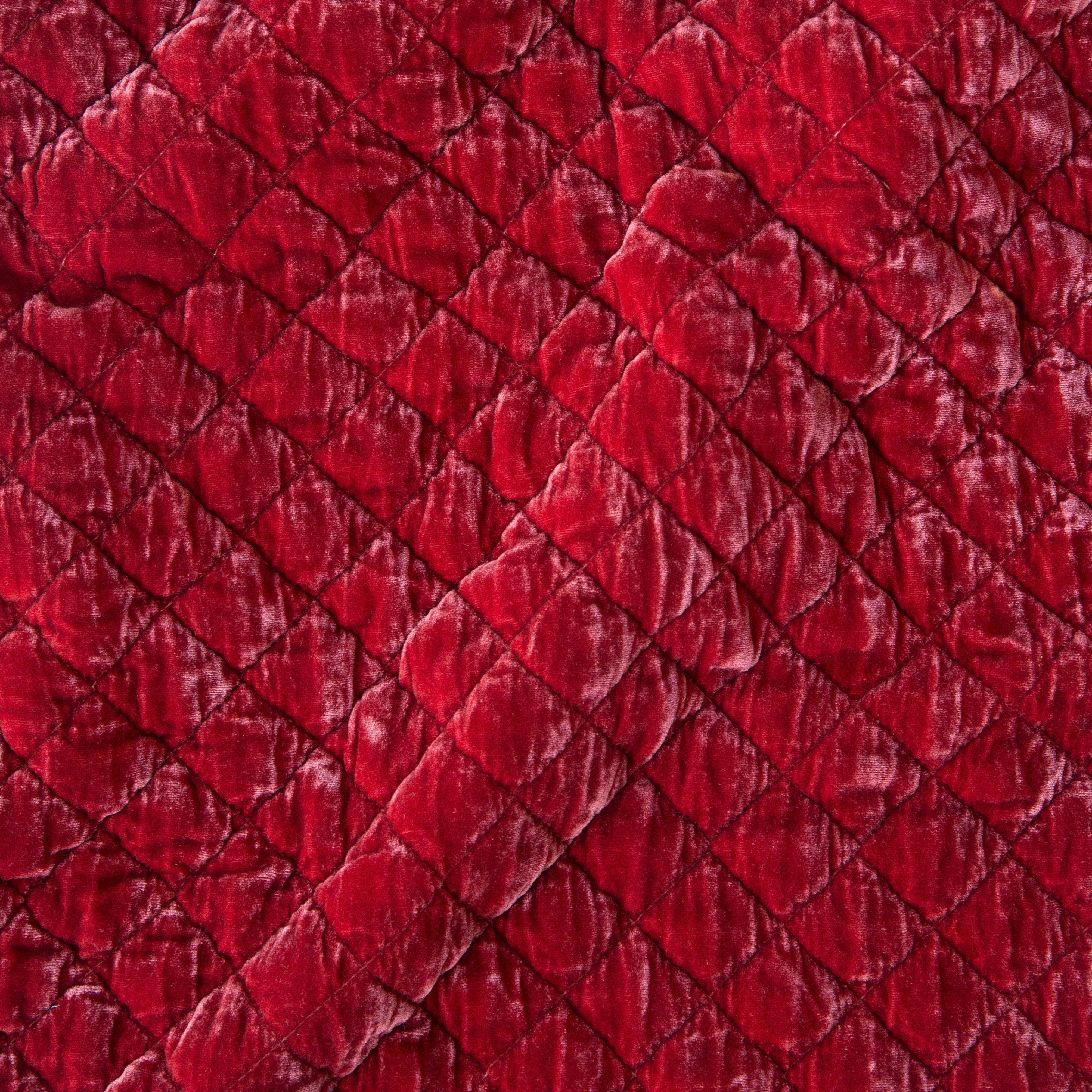 Poppy: Close-up of quilted silk velvet in poppy, a vibrant reddish pink.