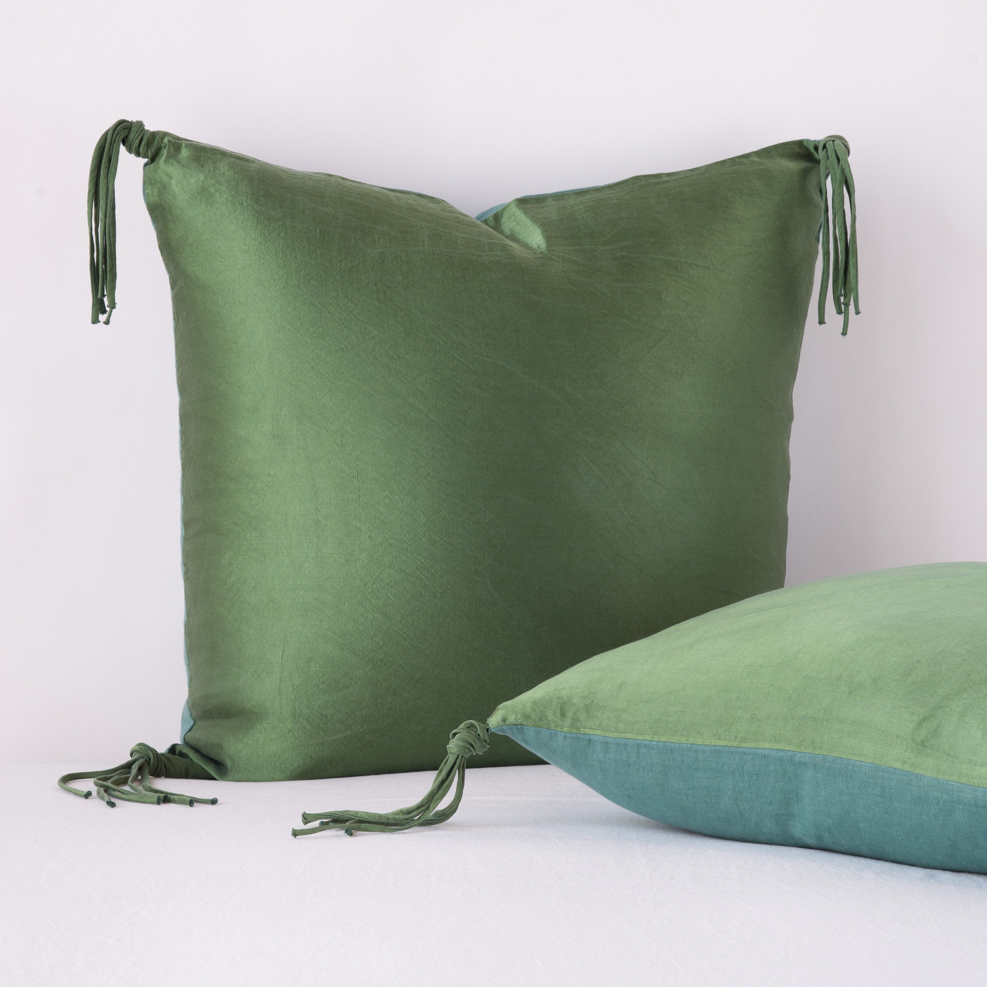 [allvariants]: Taline shams against a white background. One leaning upright and one laid flat, showcasing midweight linen reverse - jade.