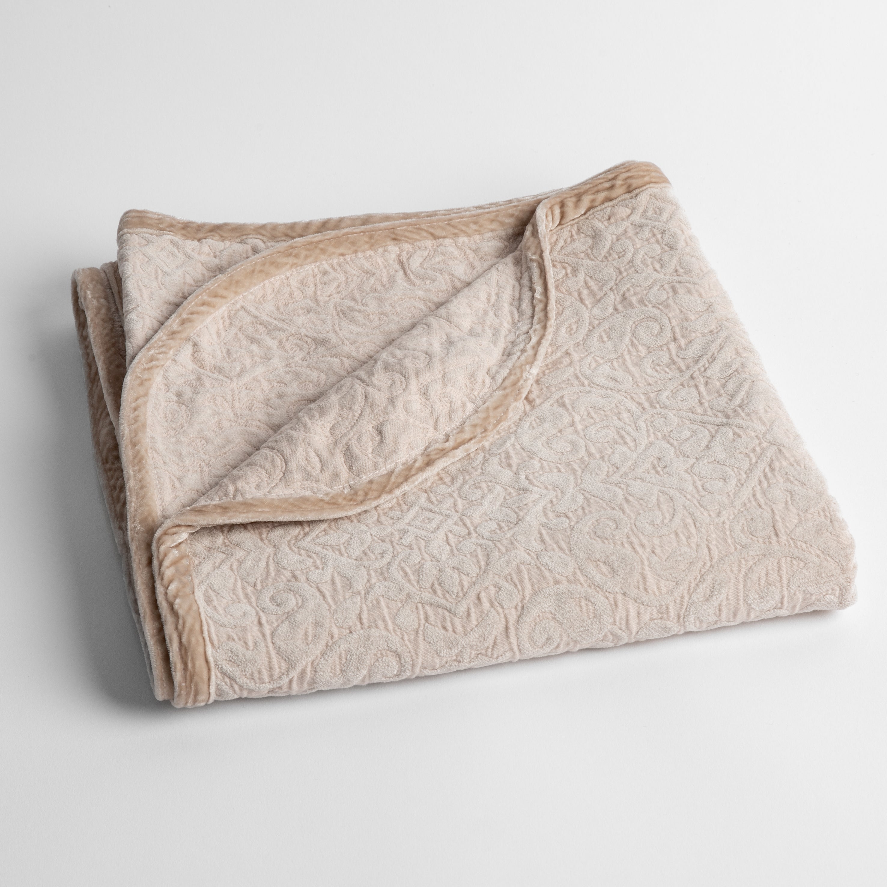 Pearl: a folded cotton chenille baby blanket trimmed in silk velvet shot overhead at a slight angle against a white background. 