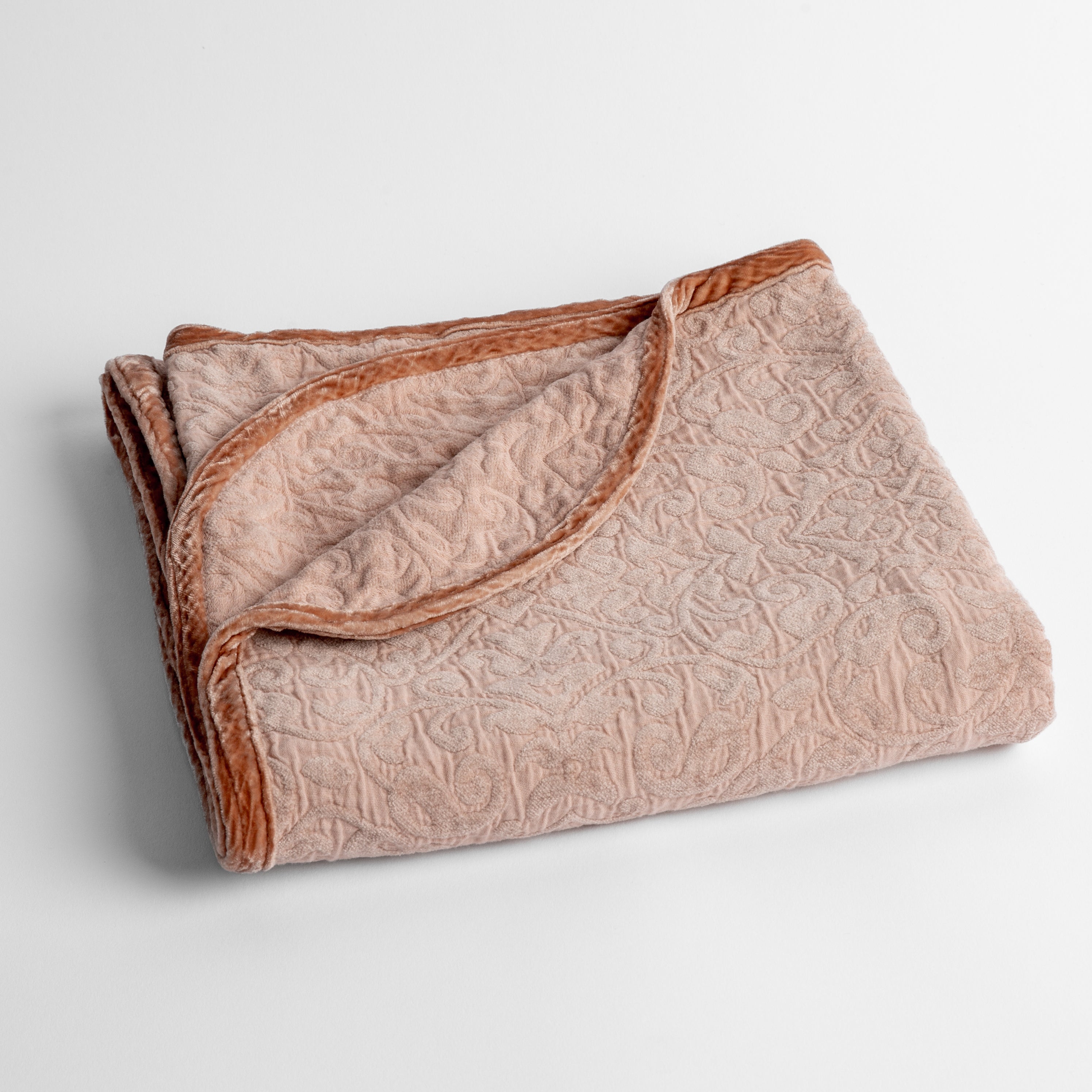 Rouge: a folded cotton chenille baby blanket trimmed in silk velvet shot overhead at a slight angle against a white background. 
