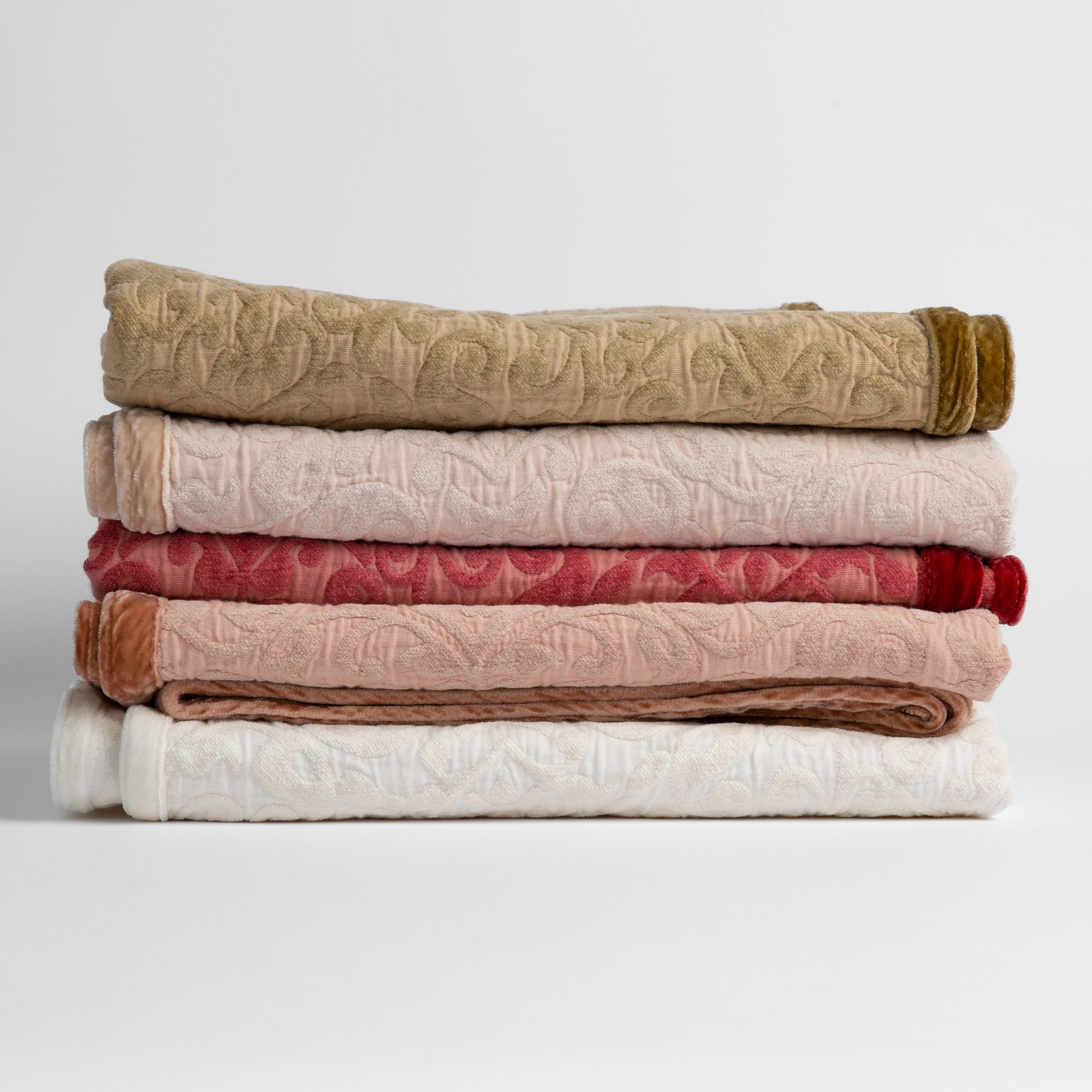 : stack of cotton chenille baby blankets in honeycomb, pearl, poppy, rouge and winter white - silk velvet edges alternating sides of the stack. 