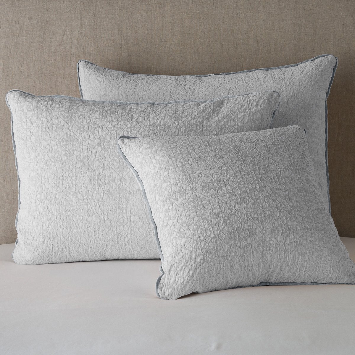 Sterling: Cotton chenille jacquard shams leaning upright against a neutral headboard.