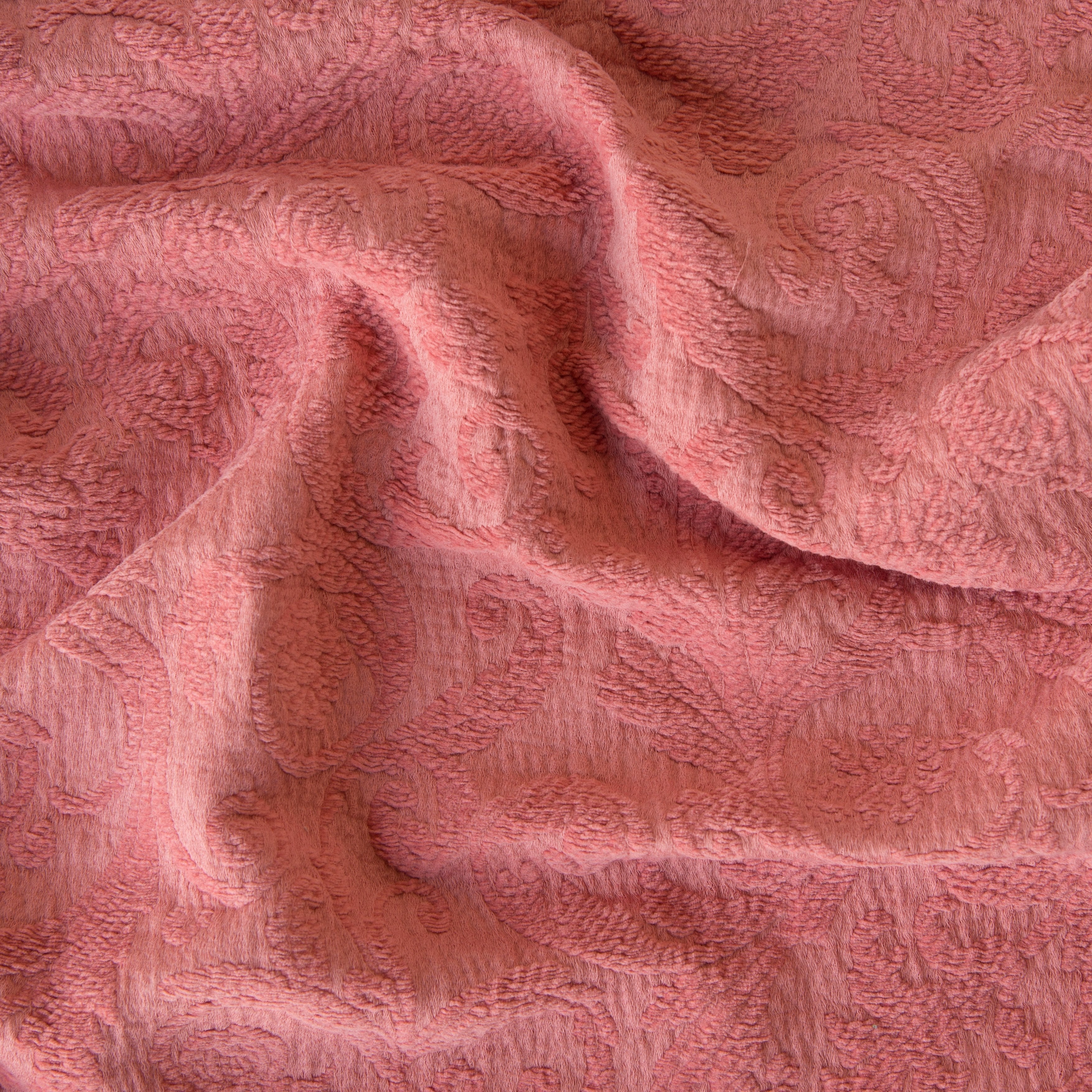 Poppy: A close up of Adele fabric in poppy, a warm coral pink. The fabric is rumpled to show the cotton damask texture.