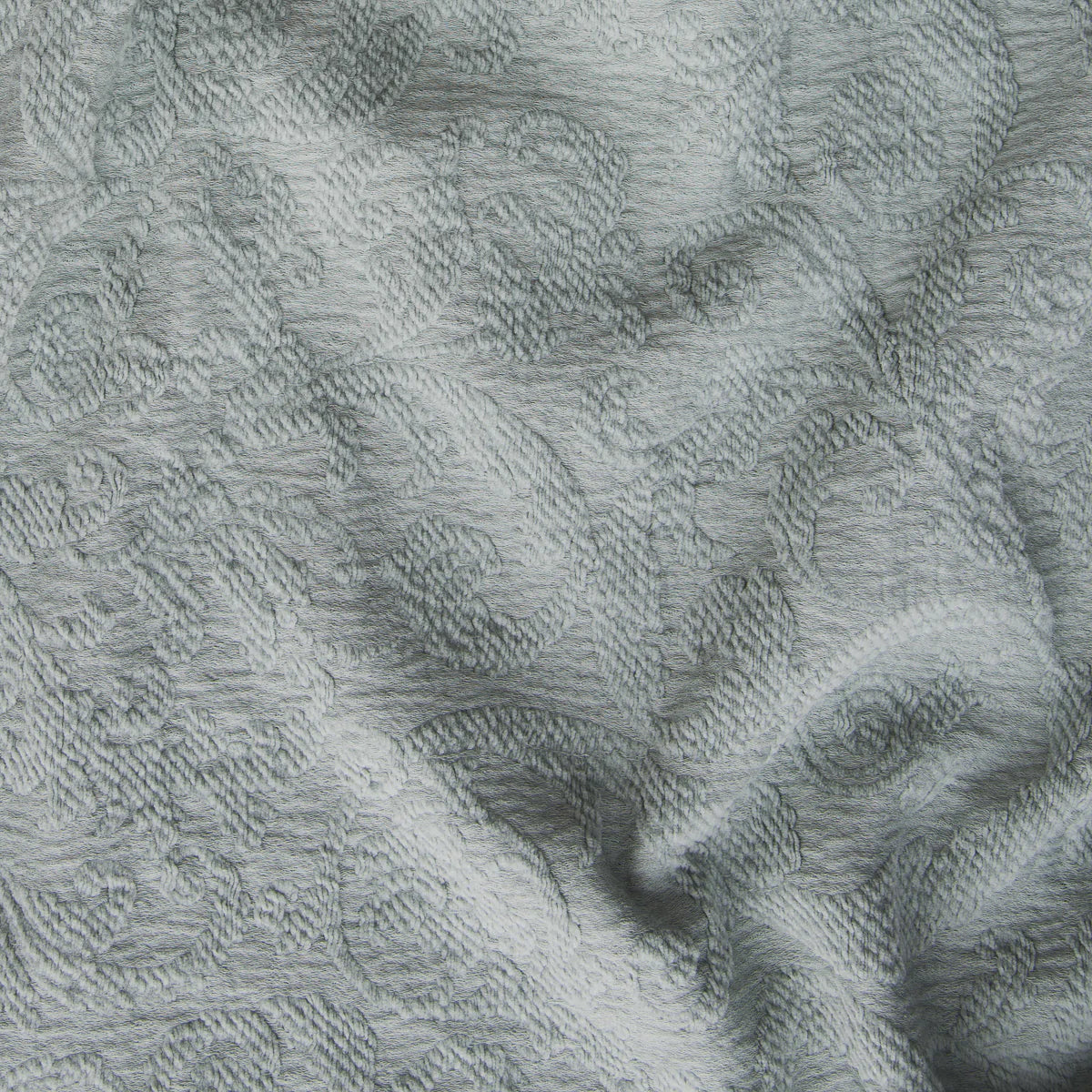 Eucalyptus: A close up of Adele fabric in eucalyptus, a soft light green. The fabric is rumpled to show the cotton damask texture.