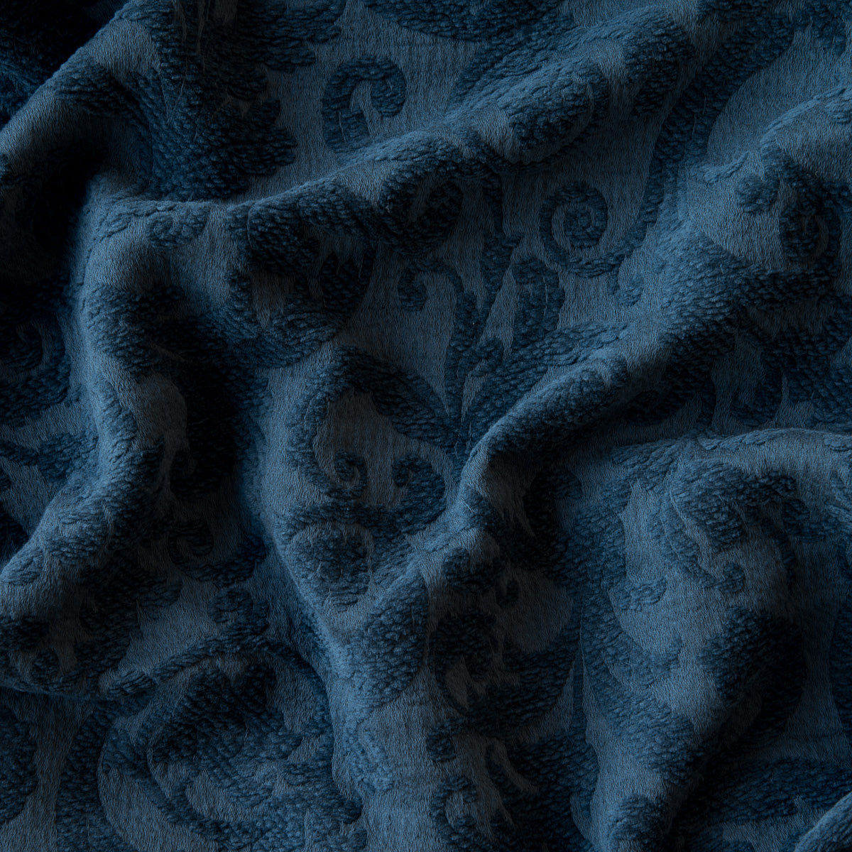 Midnight: A close up of Adele fabric in midnight, a dark blue tone; the fabric is gently rumpled to showcase the damask pattern. 