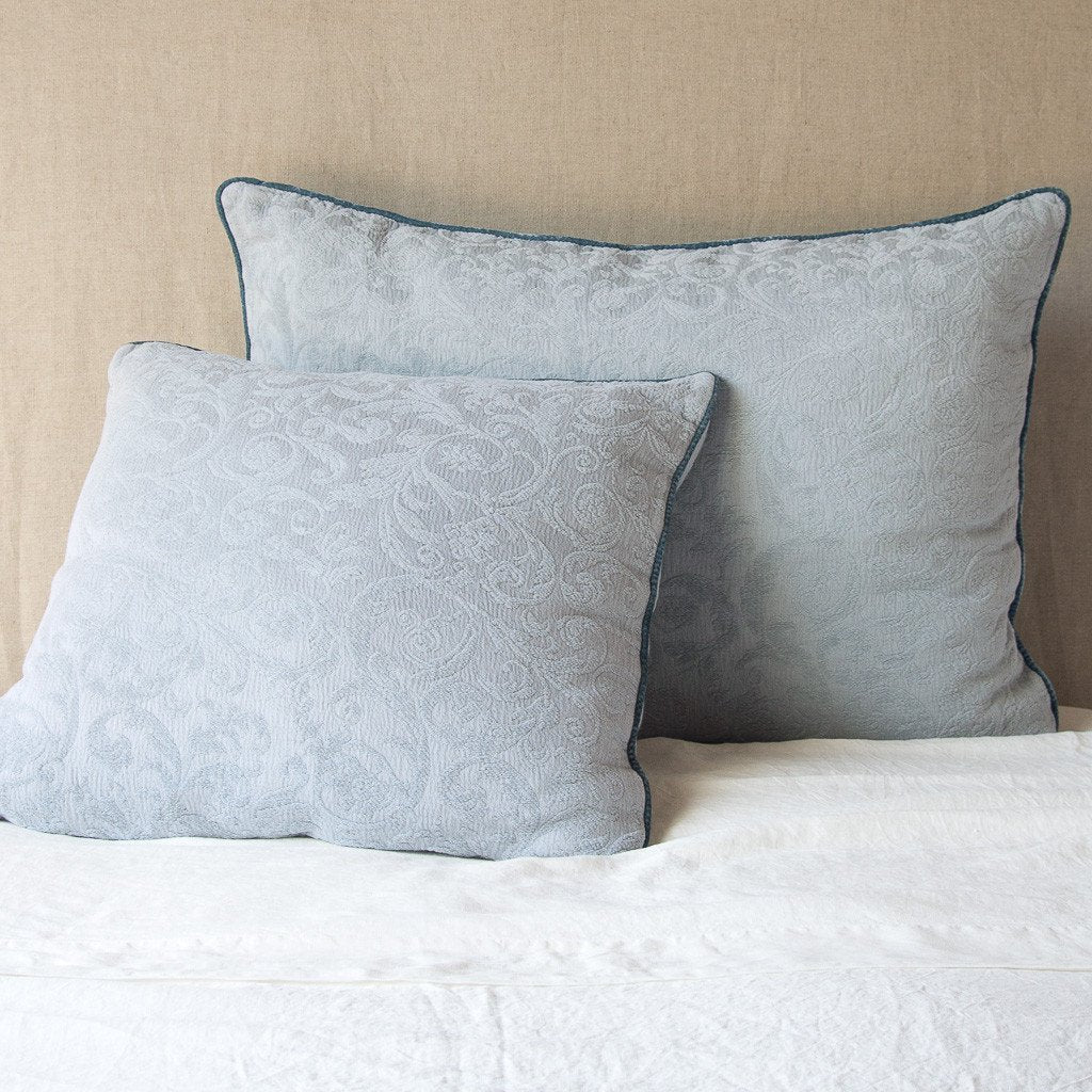 Mineral: Two shams , shown in euro and deluxe sizes, leaning against a neutral toned headboard on white bedding.