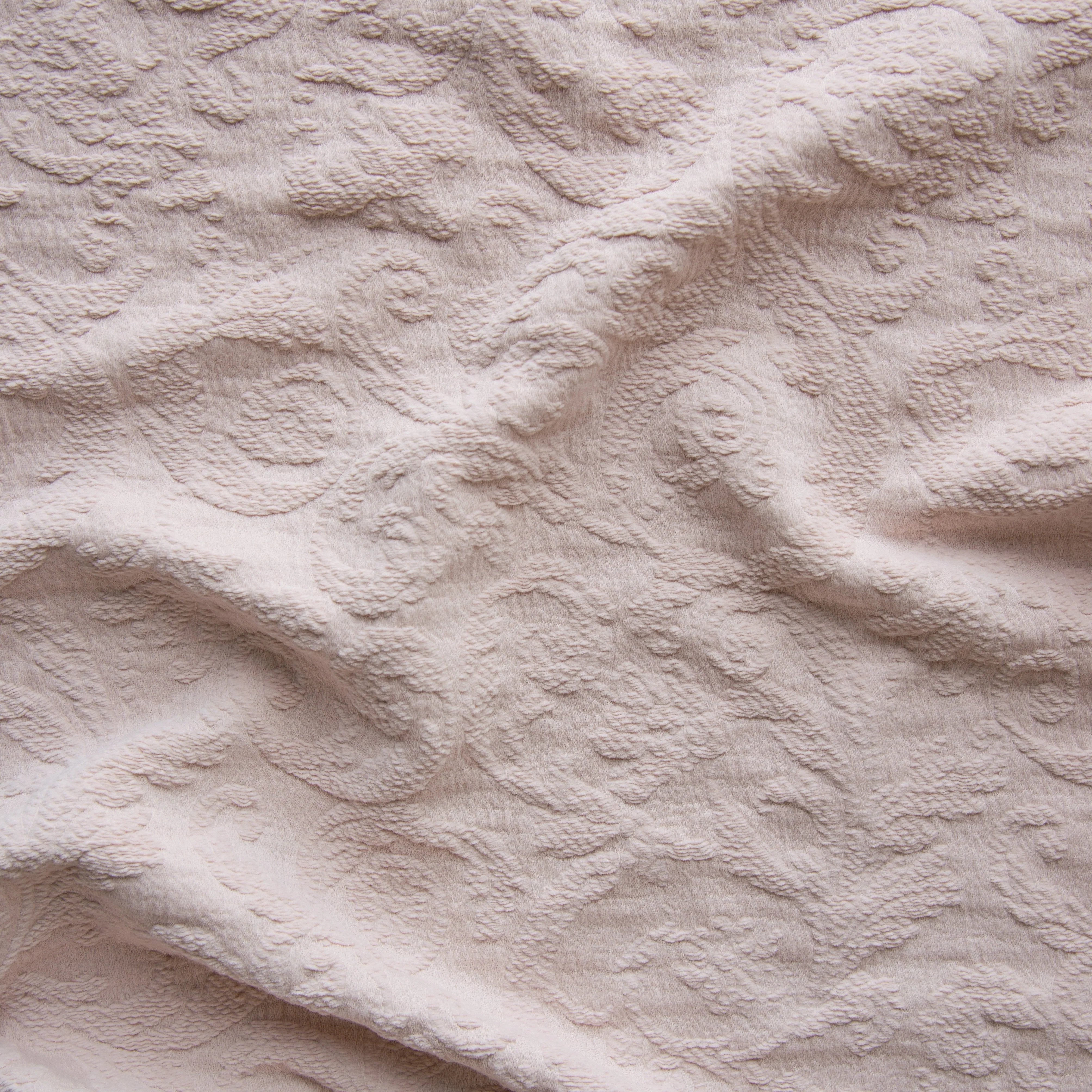 Pearl: A close up of Adele fabric in pearl, a nude-like, soft rose pink tone. The fabric is rumpled to show the cotton damask texture.