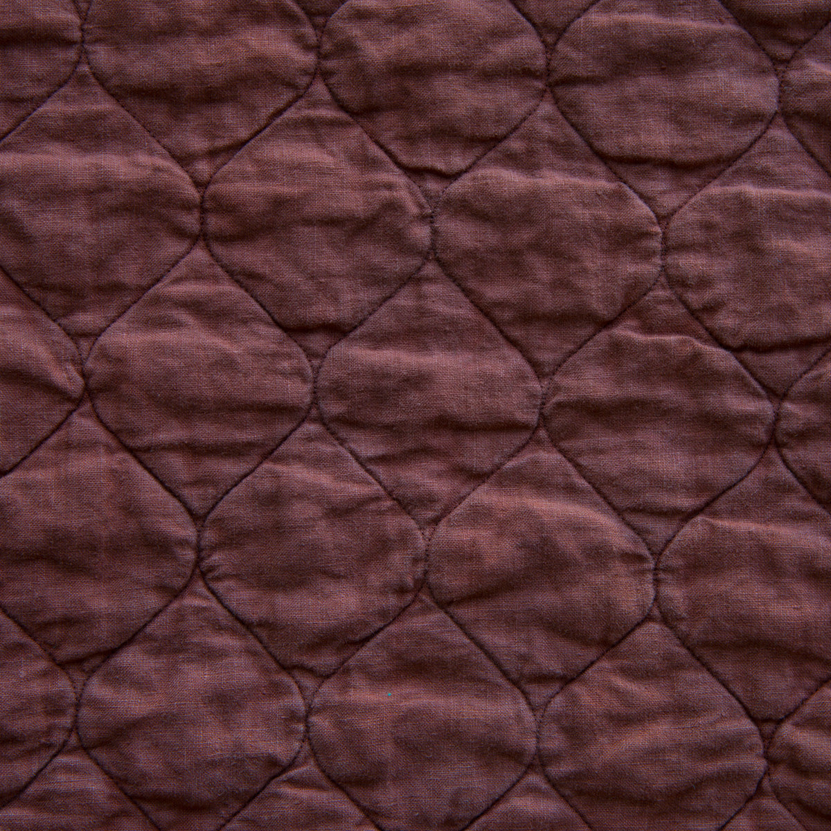 Mahogany: A close up of Austin quilted midweight linen in mahogany, a deep, earthen, reddish brown. 