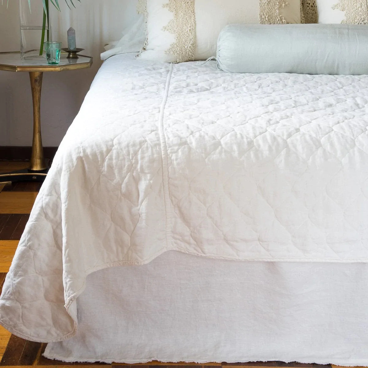 [allvariants]: Austin bed skirt in winter white, shown from the end of the bed, layered with a quilted coverlet in the same tone.