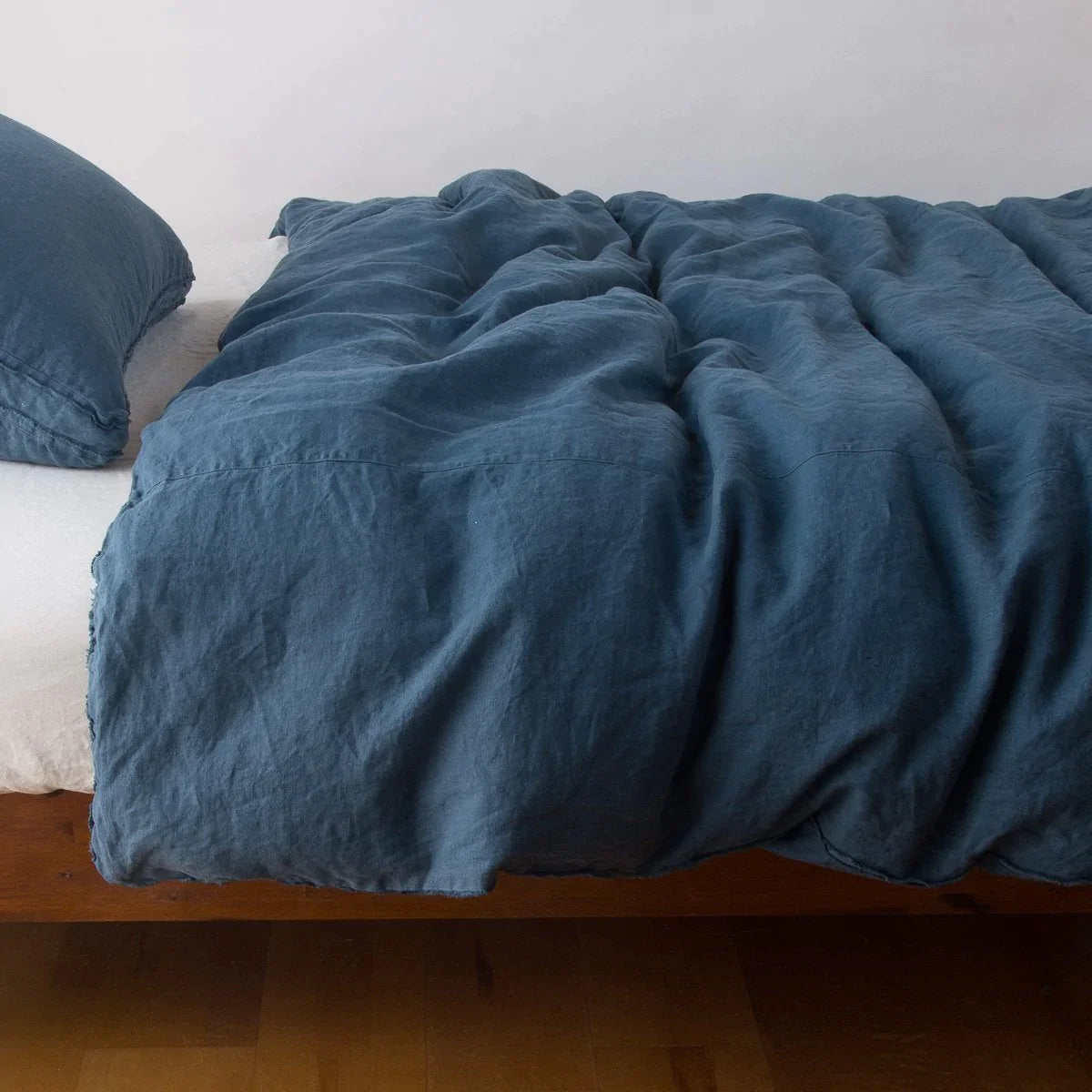 Midnight: Midweight linen duvet cover in midnight on a bed, side view.