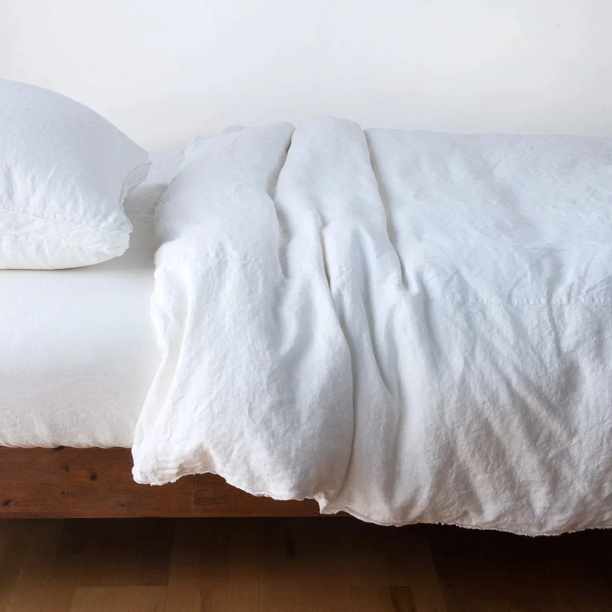 White: Midweight linen duvet cover in white on a bed, side view.