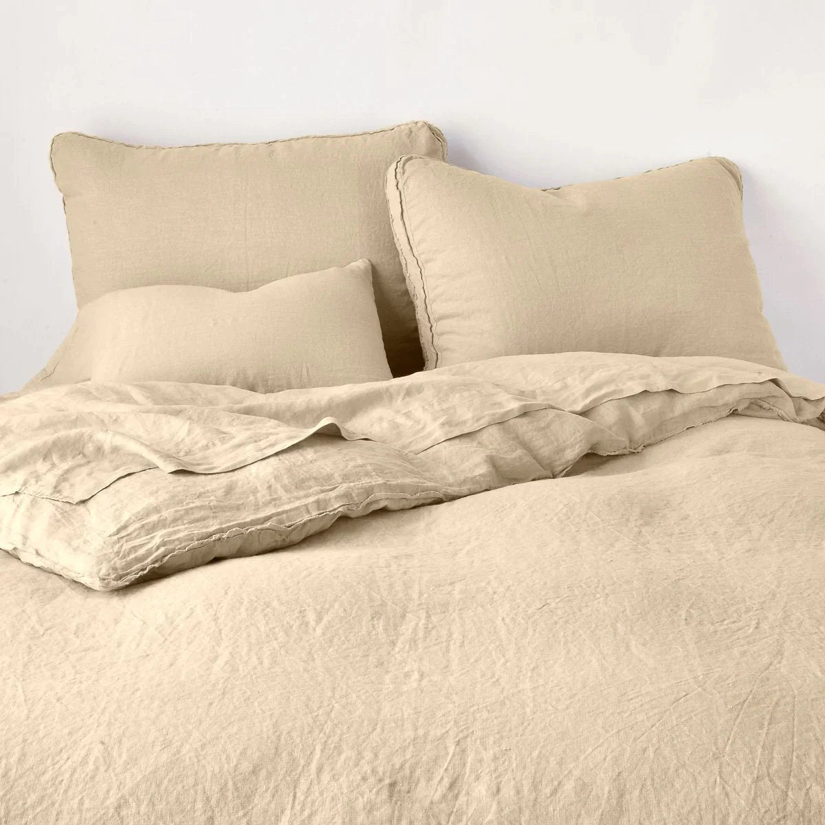 Honeycomb: Midweight linen shams shown from foot of bed, leaning against a plain background with monochromatic bedding. 