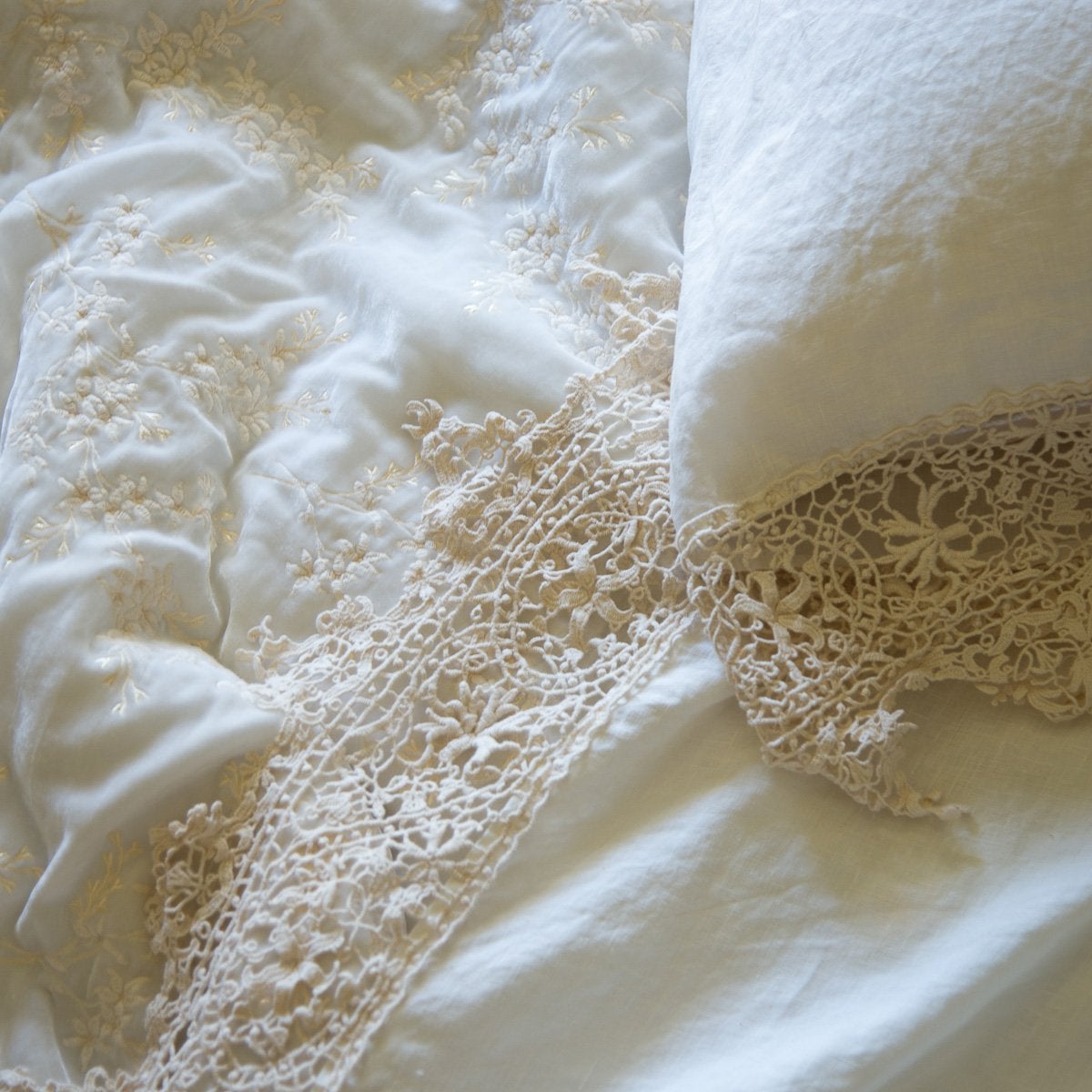 : Close up of Frida lace detail in winter white flat sheet and matching pillowcase, highlighting the antique cotton lace pattern - overhead view.