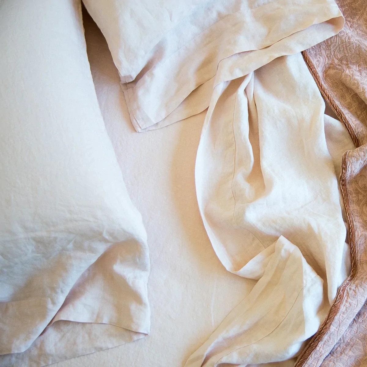 : Rumpled linen sheeting and pillow cases with Vienna cotton chenille jacquard in soft pink tones - overhead view.