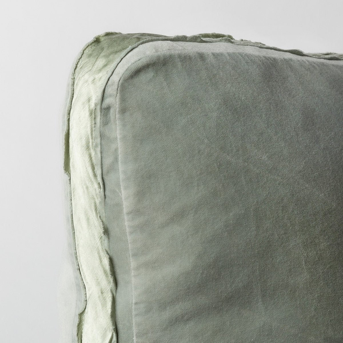 Eucalyptus: : Corner detail close-up of cotton velvet 24 by 24 pillow, showcasing charmeuse gusset and raw edge trim.