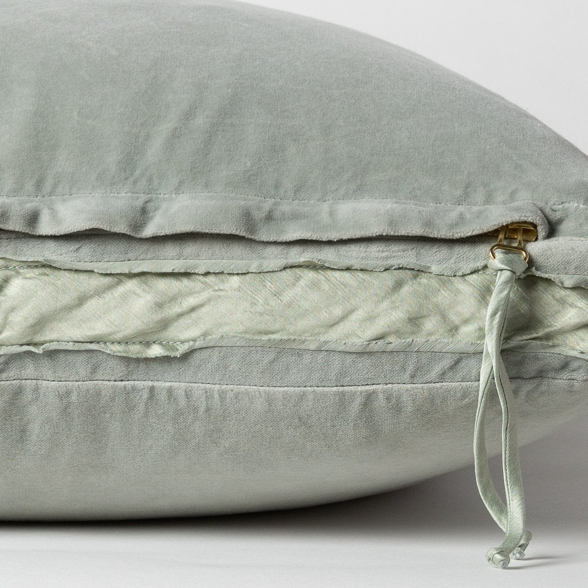 Eucalyptus: Close-up of charmeuse gusset, raw-edge trim, and brass zipper detail on Harlow pillow - side view.