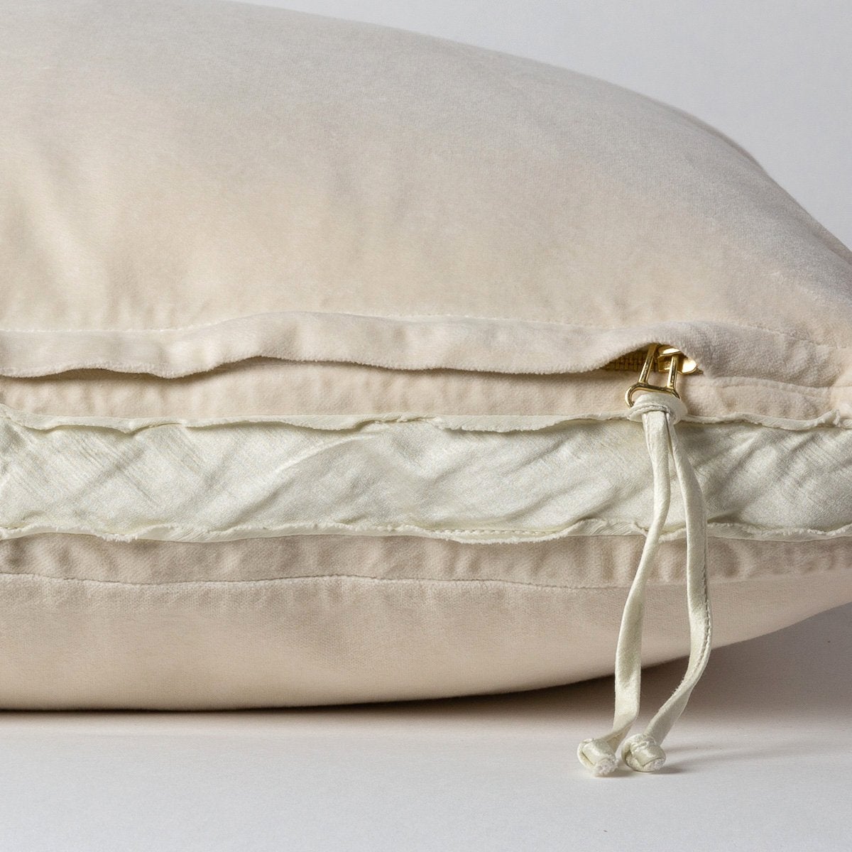 Parchment: Close-up of charmeuse gusset, raw-edge trim, and brass zipper detail on Harlow pillow - side view.