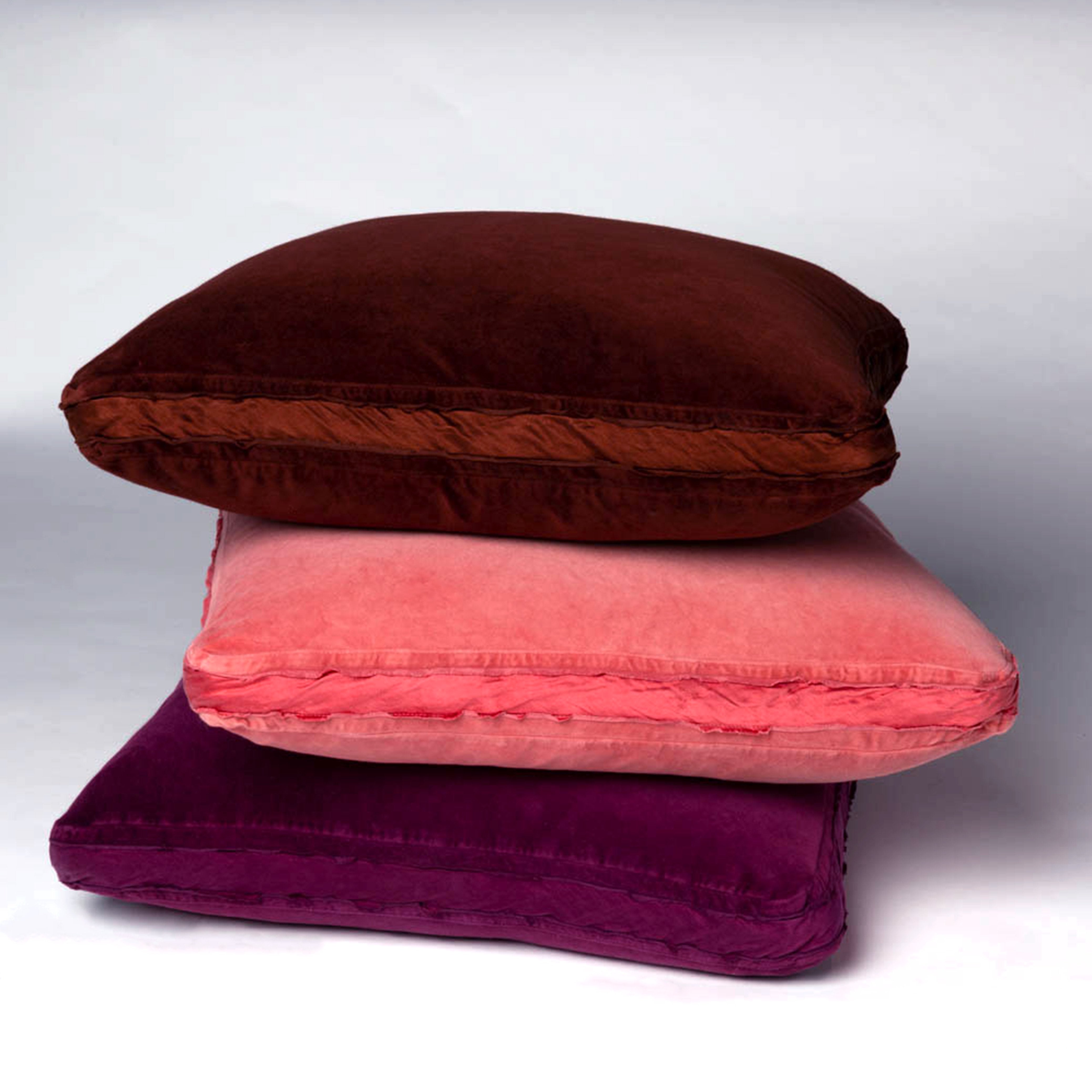 : Harlow 24 by 24 pillows stacked against a plain background, in rich pink and brown tones - side view.