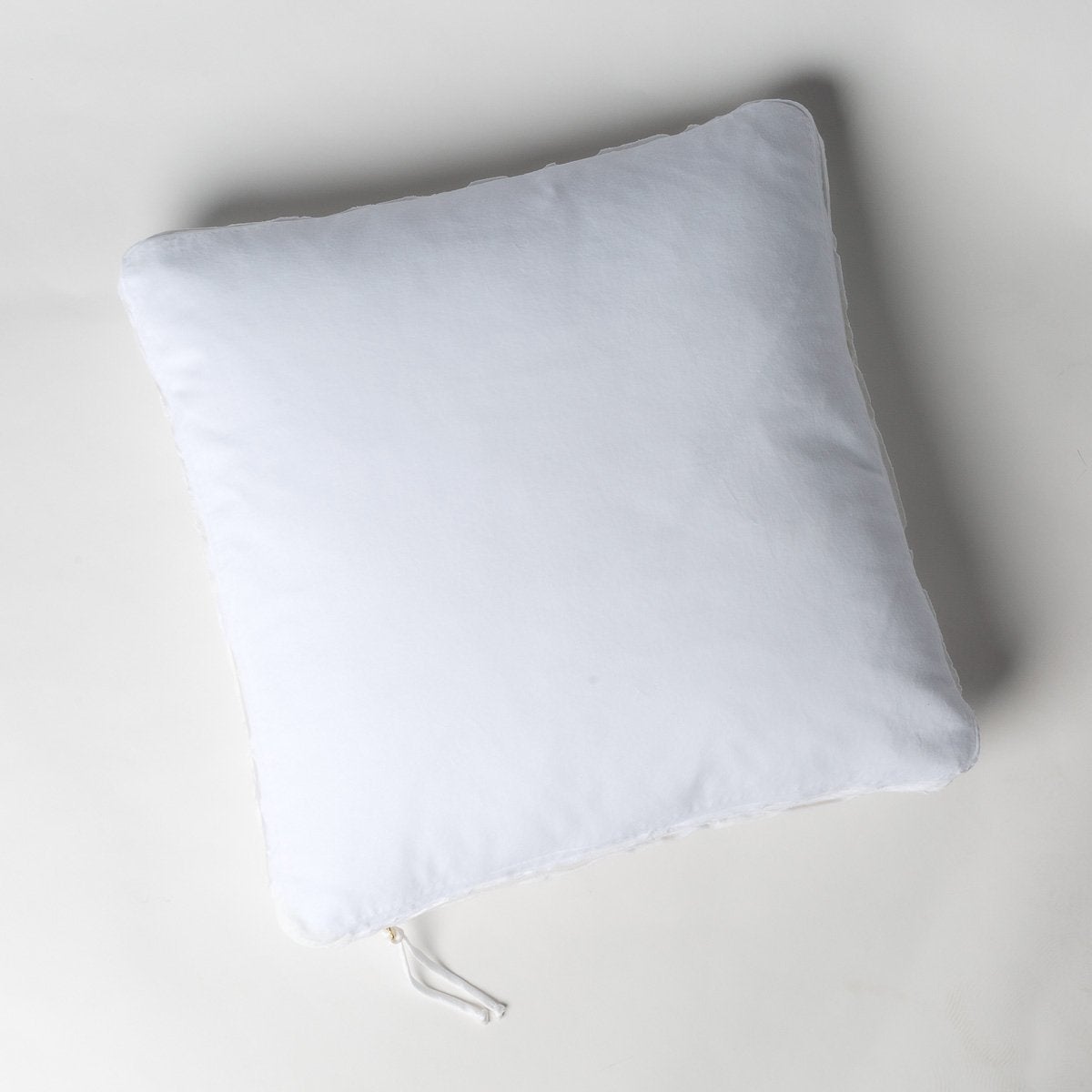White: Cotton velvet 24 by 24 pillow on a plain background - overhead view.