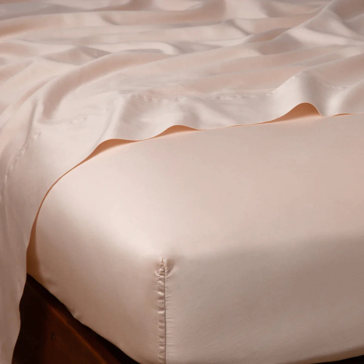 Pearl: Cotton sateen flat sheet draped over matching fitted sheet. Shown from the top corner, the flat sheet is rumpled, highlighting the shine of the fabric.