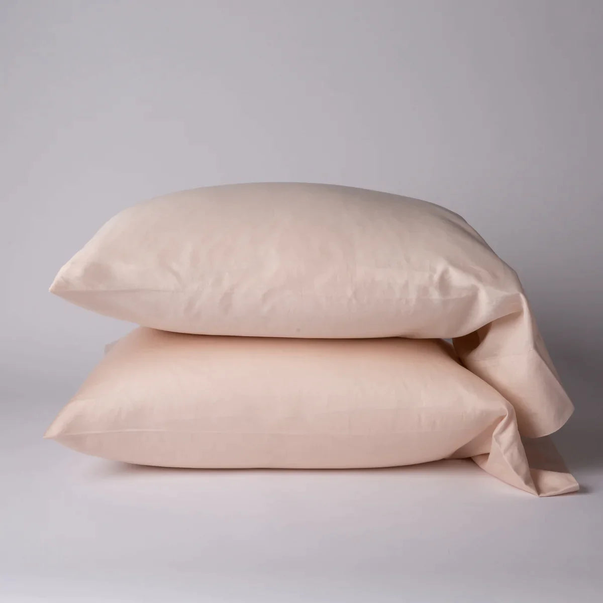 Pearl: Two cotton sateen sleeping pillows, stacked neatly against a white backdrop - side view.