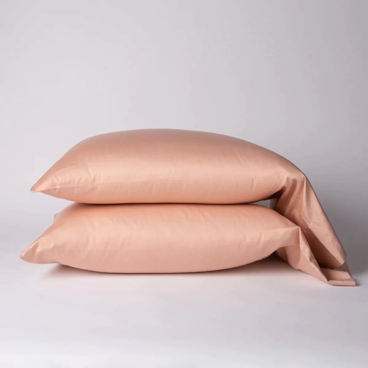Rouge: Two cotton sateen sleeping pillows, stacked neatly against a white backdrop - side view.