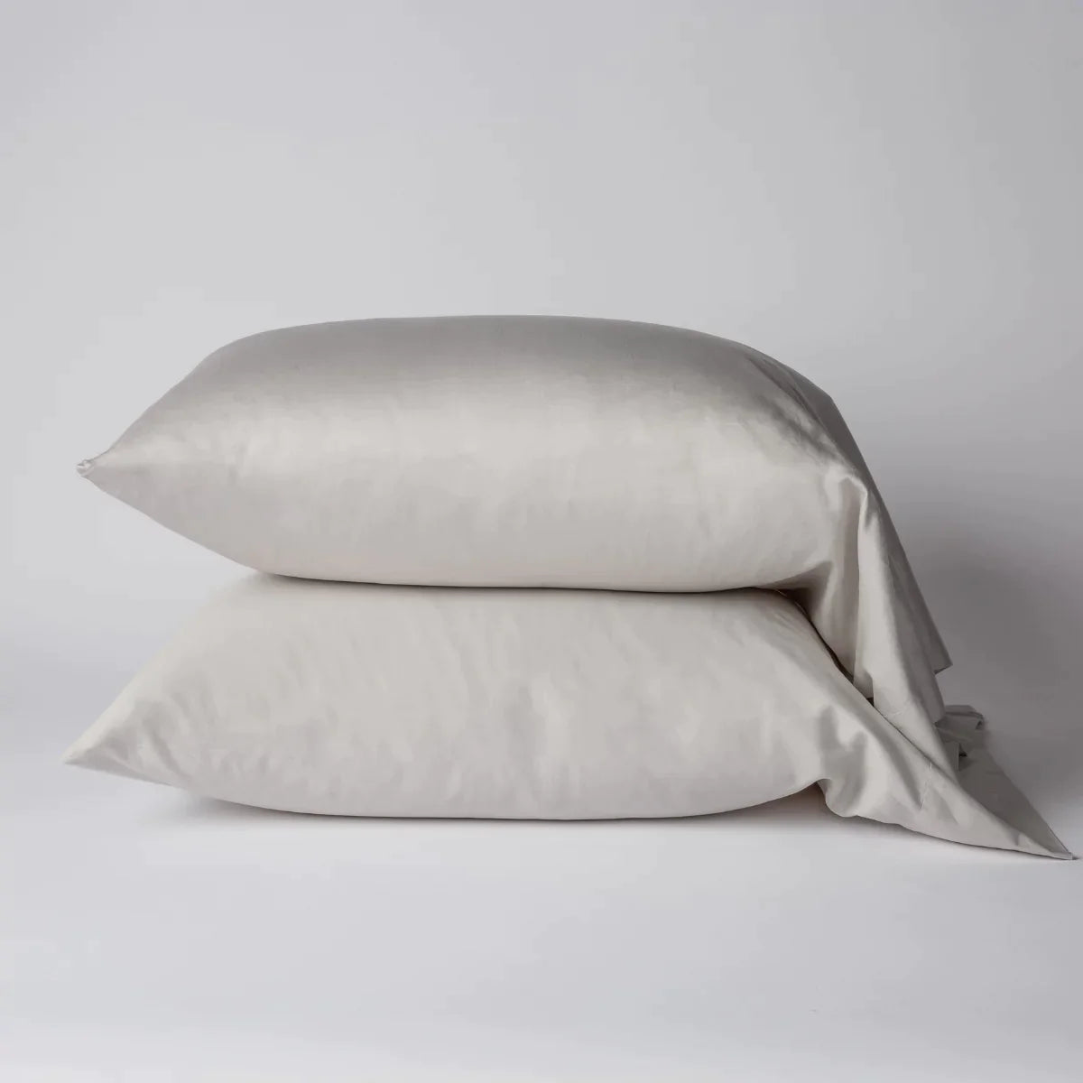 Sterling: Two cotton sateen sleeping pillows, stacked neatly against a white backdrop - side view.
