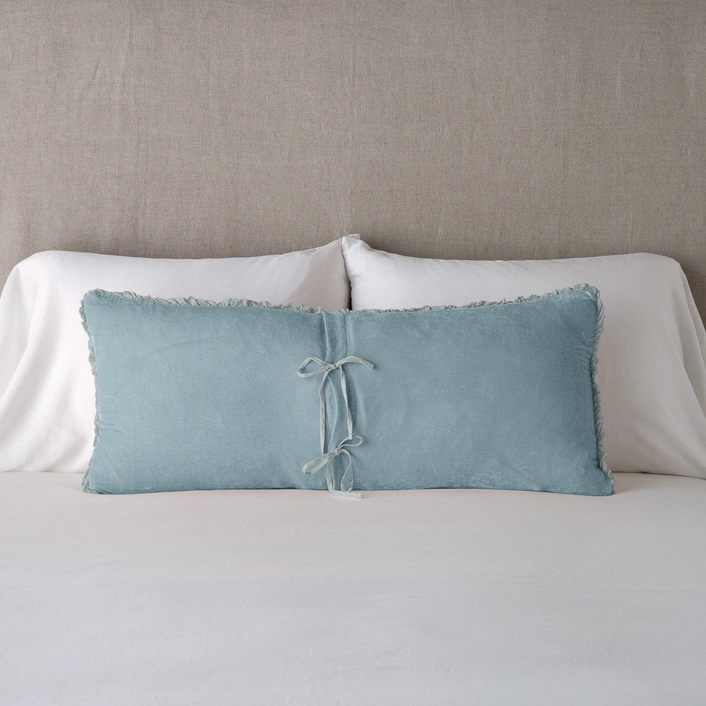 Cloud: Silk velvet lumbar pillow with petite ruffle leaning upright and backwards against neutral bedding and headboard, showcaseing the silk charmeuse tie closures.