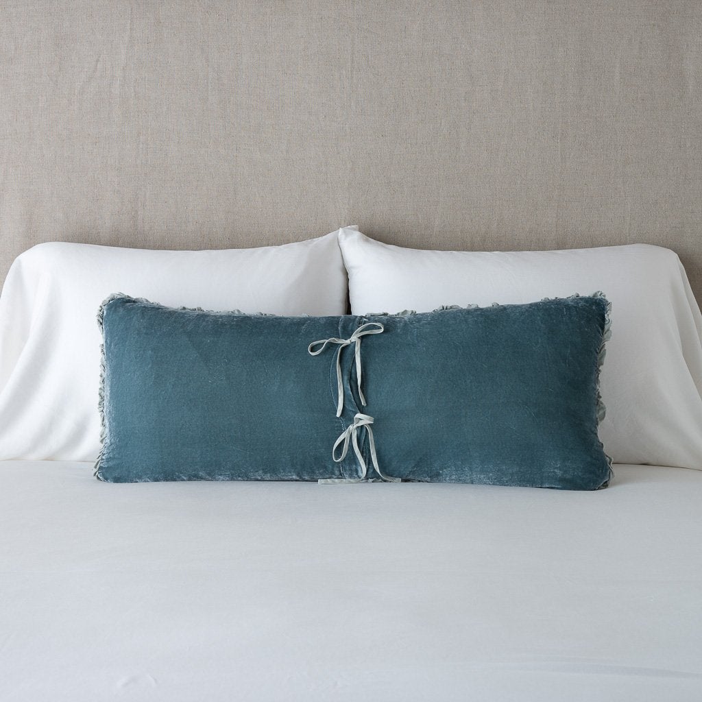 Mineral: Silk velvet lumbar pillow with petite ruffle leaning upright and backwards against neutral bedding and headboard, showcaseing the silk charmeuse tie closures.