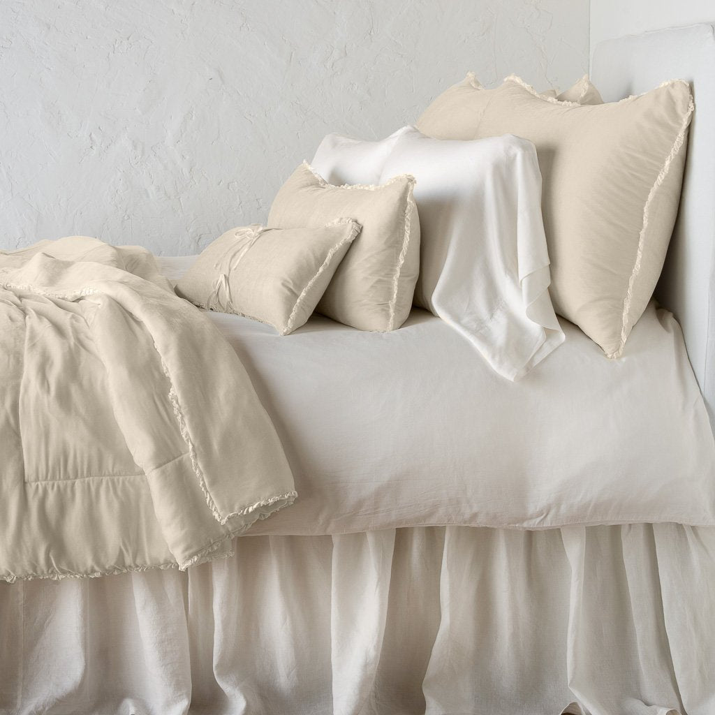 Parchment: Silk velvet throw blanket with petite ruffle, draped across a monochromatic bed - side view.