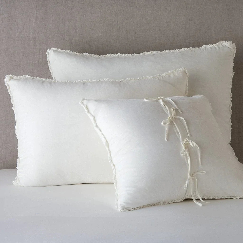 Winter White: Silk velvet  shams with a petite ruffle leaning upright against a neutral headboard. The front sham is backwards, showcasing the charmeuse tie closures.