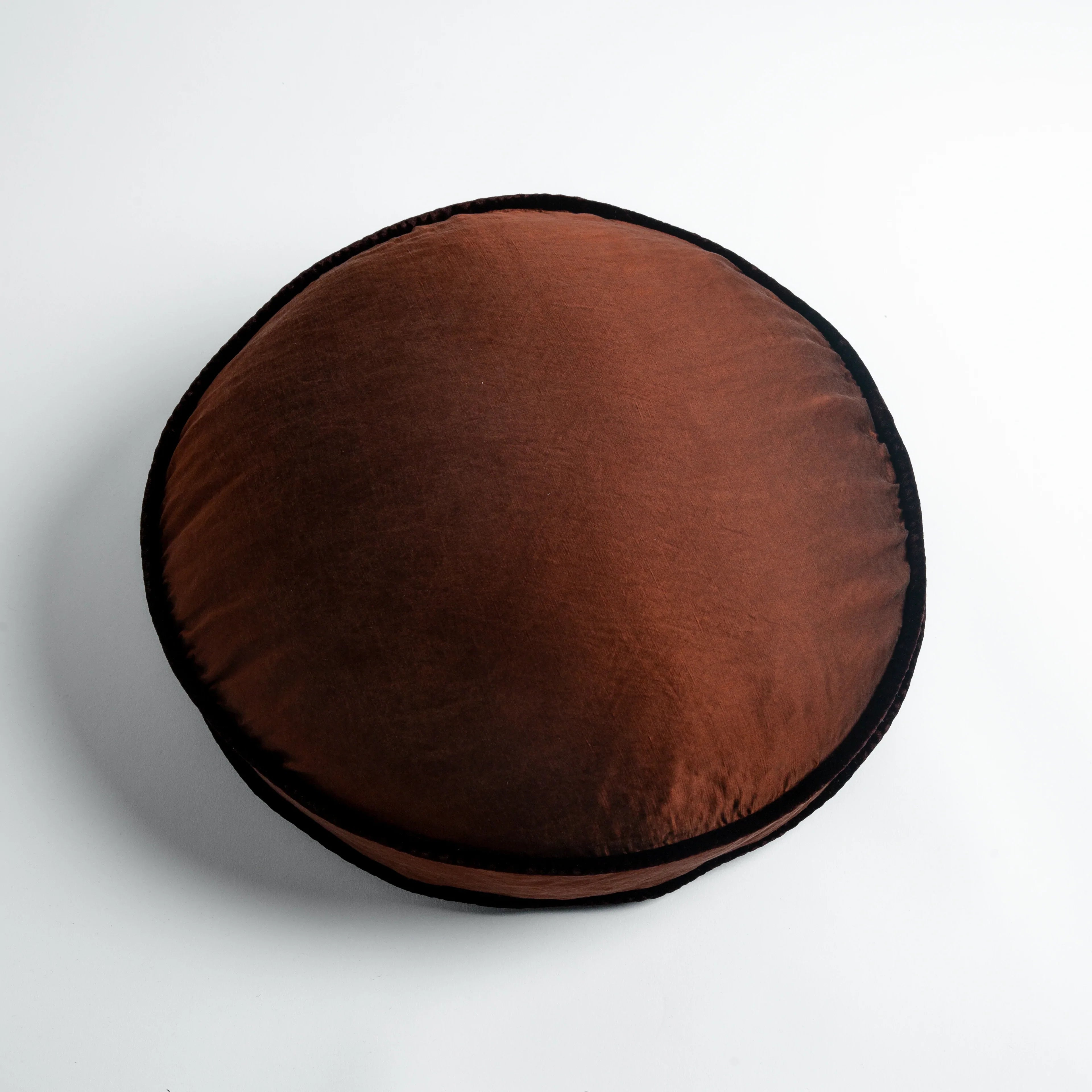 Mahogany: 18" round charmeuse pillow with silk velvet trim at gusset shot from overhead on a white background