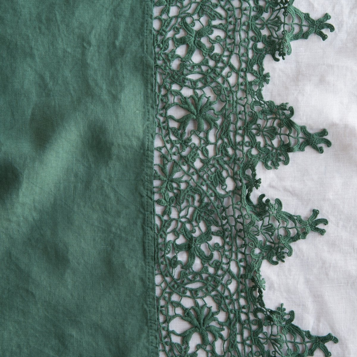 Jade: A close up of Frida, an antique cotton lace trim on a linen body, shown in jade, a rich, verdant green with subtle blue undertones.