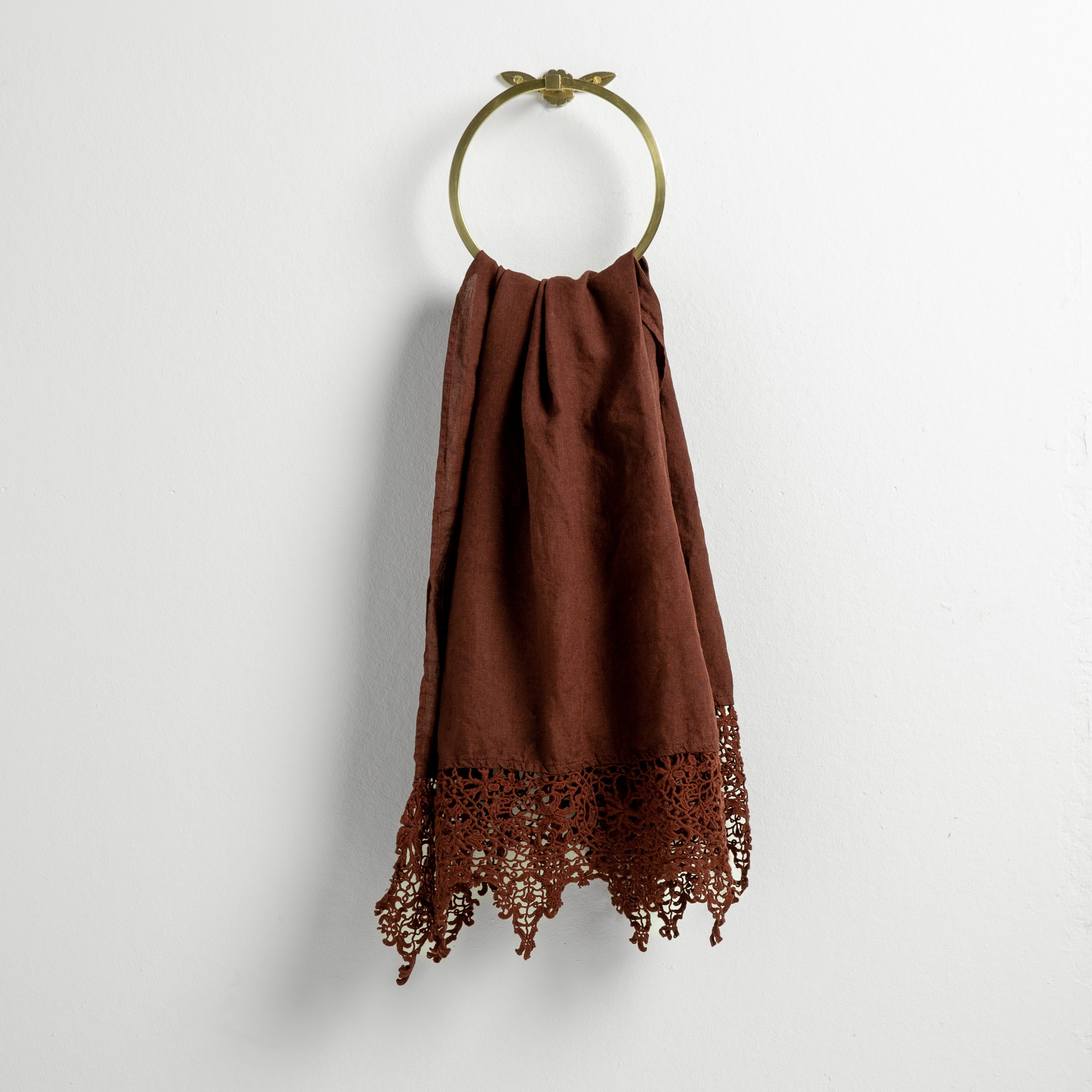 Mahogany: Lace trimmed linen guest towel  draped through a decorative towel ring against a plain white background.