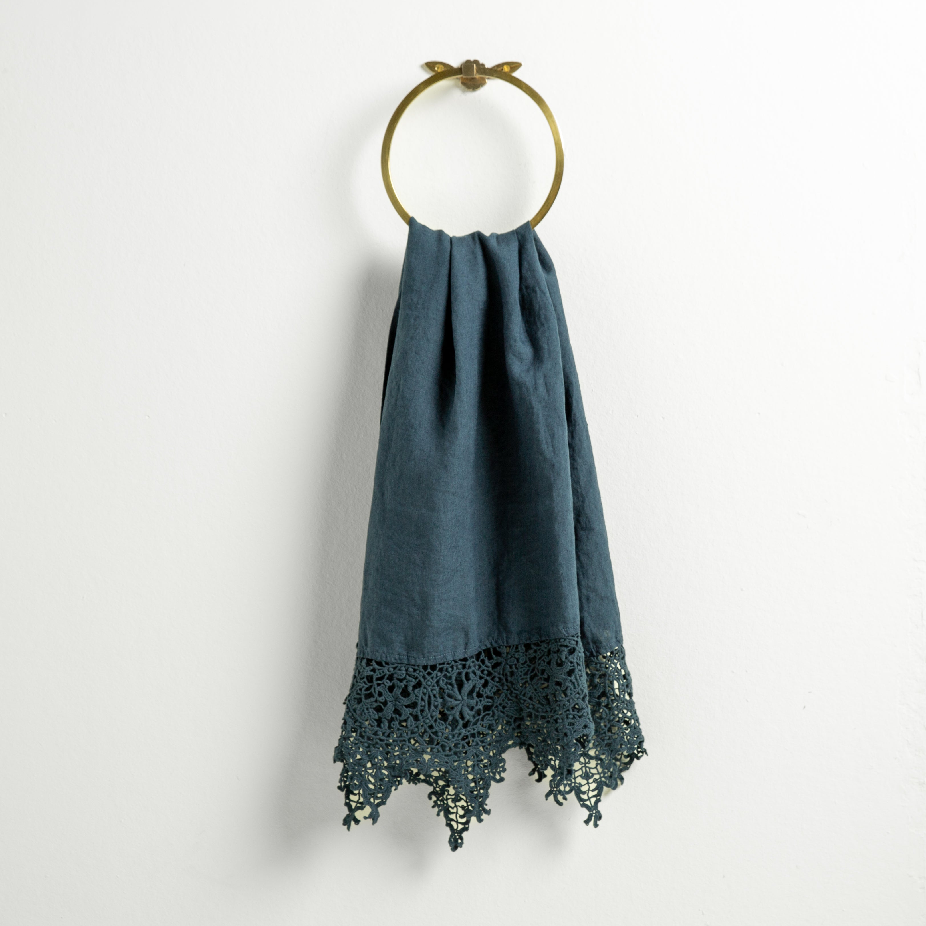Midnight: Lace trimmed linen guest towel  draped through a decorative towel ring against a plain white background.