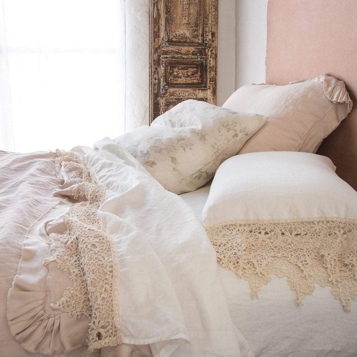 [allvariants]: Frida flat sheet in winter white, folded back over soft pink bedding, highlighting the antique cotton lace trim - close up side view.