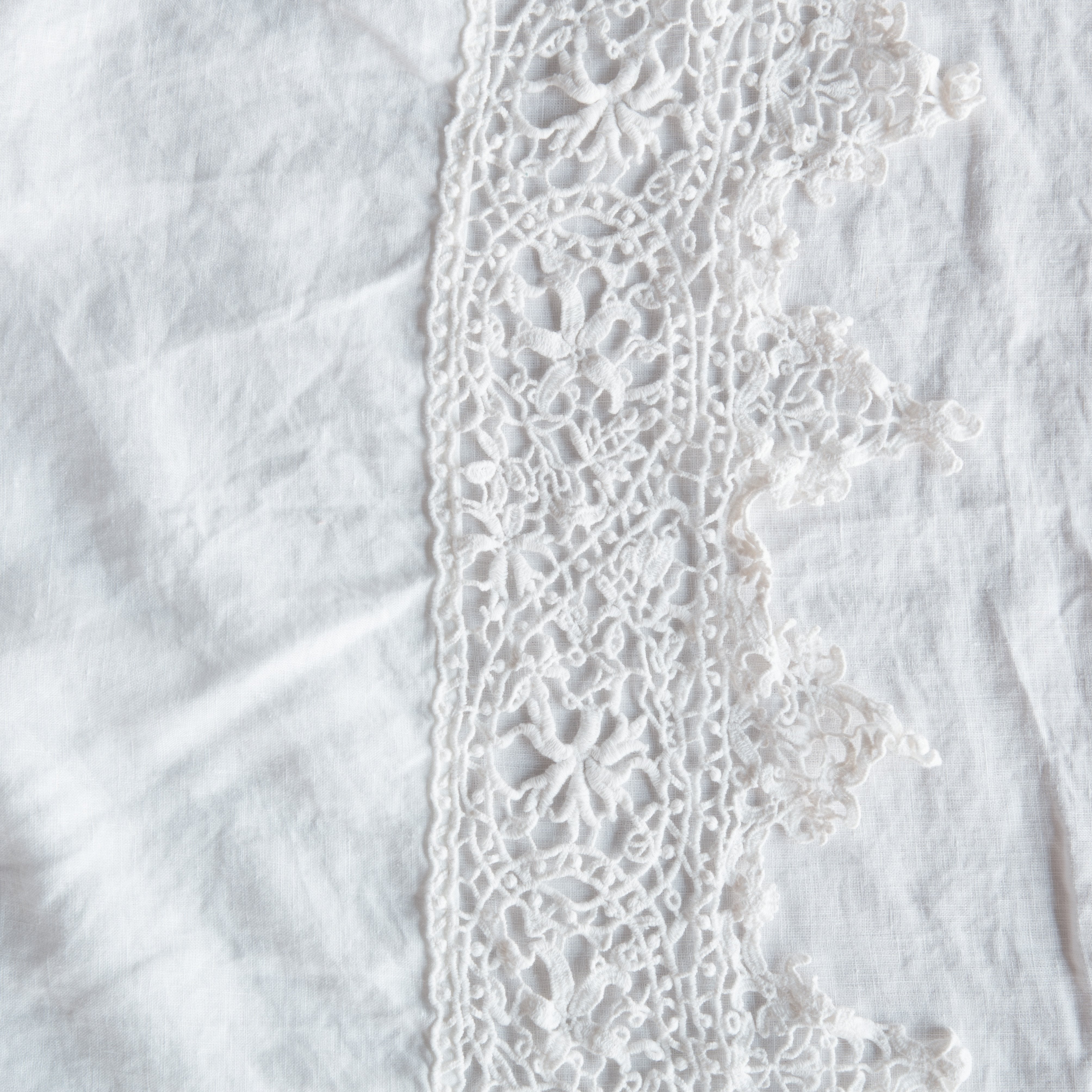 White: A close up of Frida, an antique cotton lace trim on a linen body, shown in white.