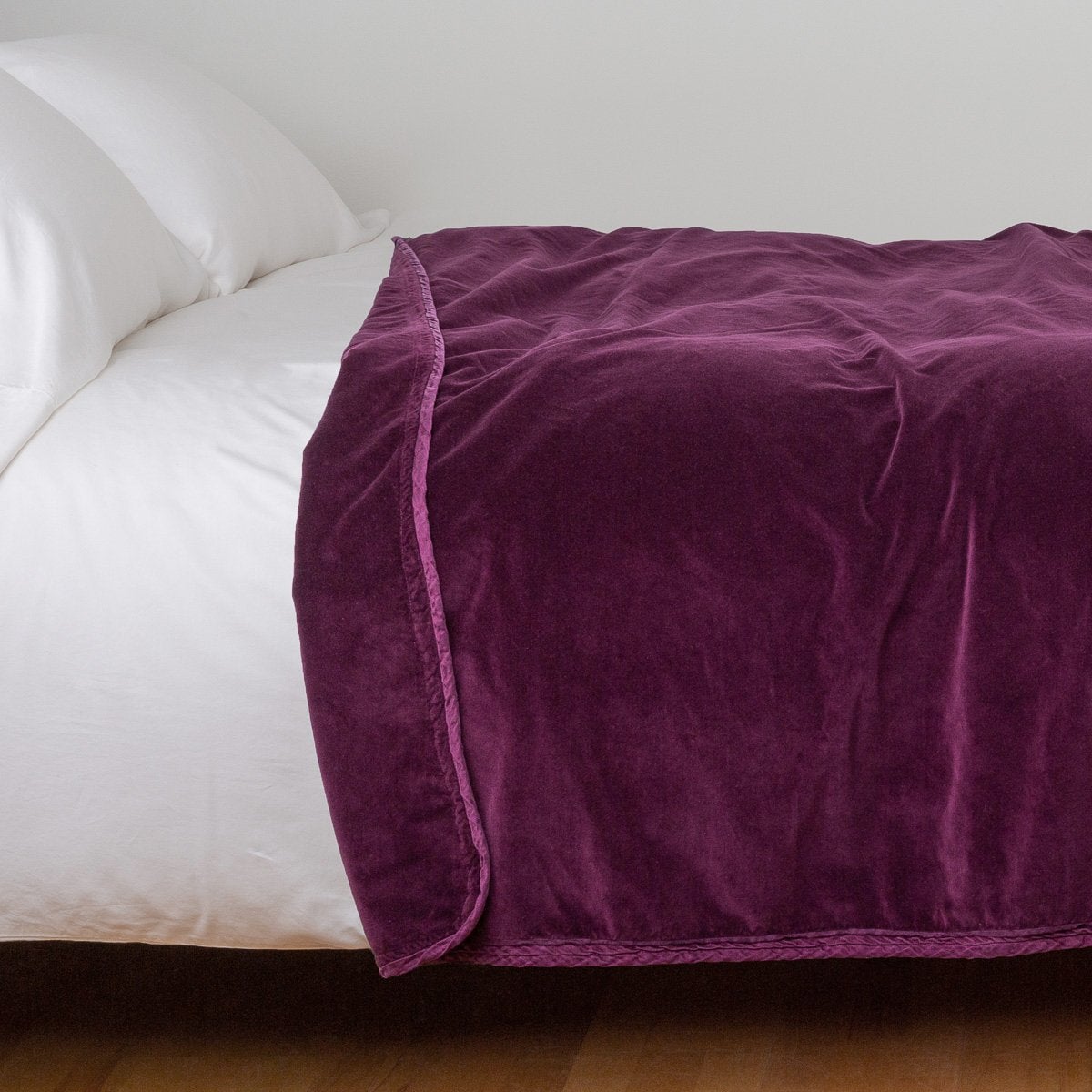 Fig: Cotton velvet blanket, draped on a white bed with corner folded back - side view.