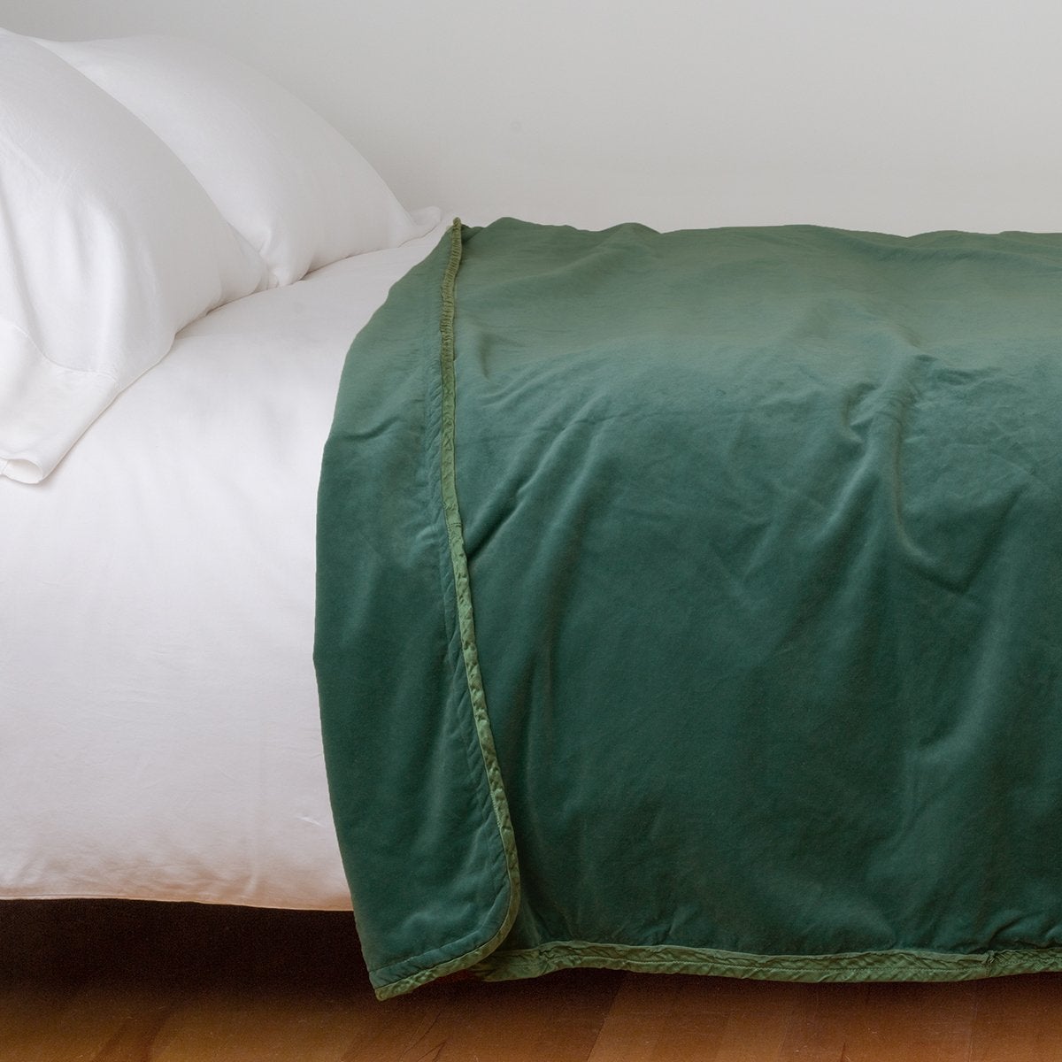 Jade: Cotton velvet blanket, draped on a white bed with corner folded back - side view.