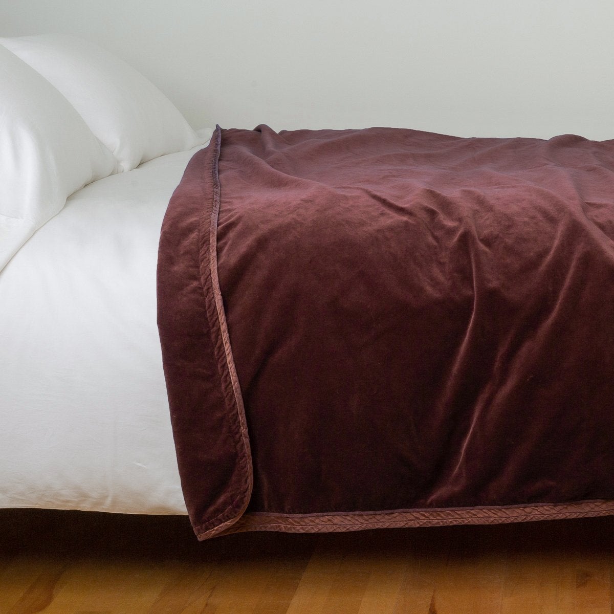 Mahogany: Cotton velvet blanket, draped on a white bed with corner folded back - side view.