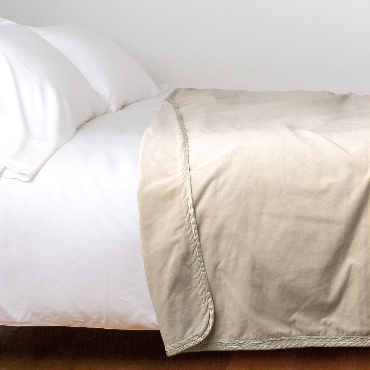 Parchment: Cotton velvet blanket, draped on a white bed with corner folded back - side view.