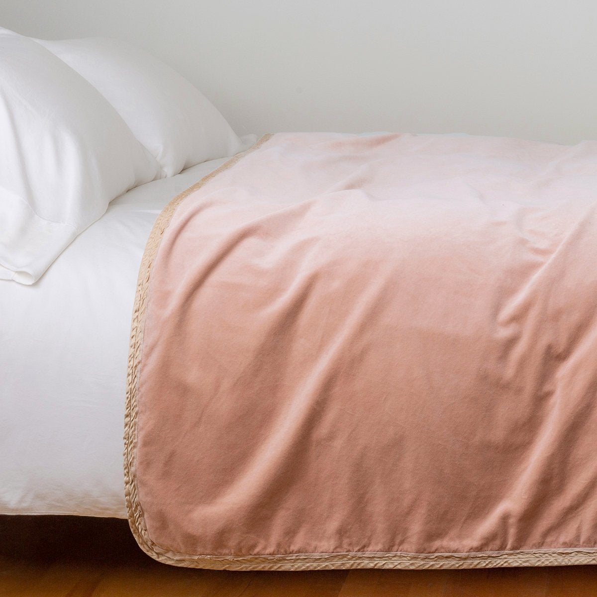 Rouge: Cotton velvet bed end sized blanket, draped on a white bed - side view.